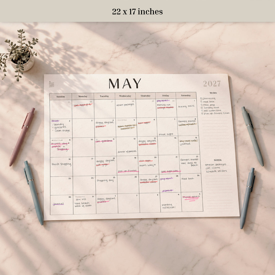2027 12-Month Flat Desk Calendar, 22 x 17 inches, May page filled in with pens nearby