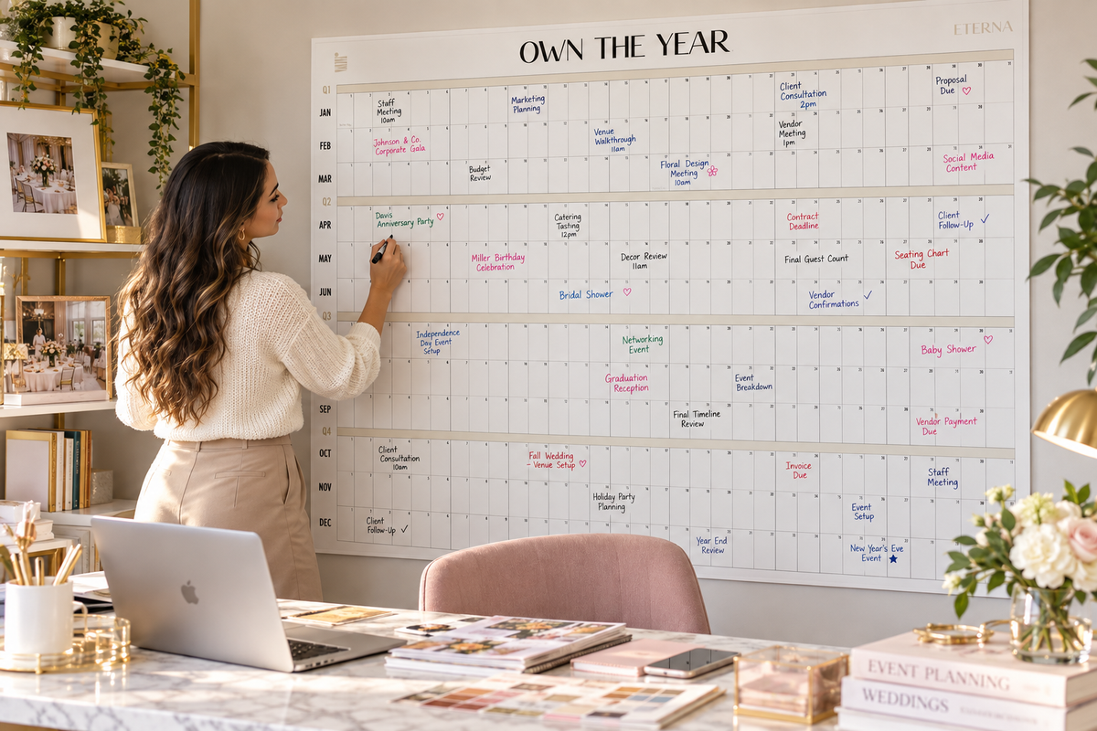 Woman writing on the Own The Year big wall calendar in a styled home office