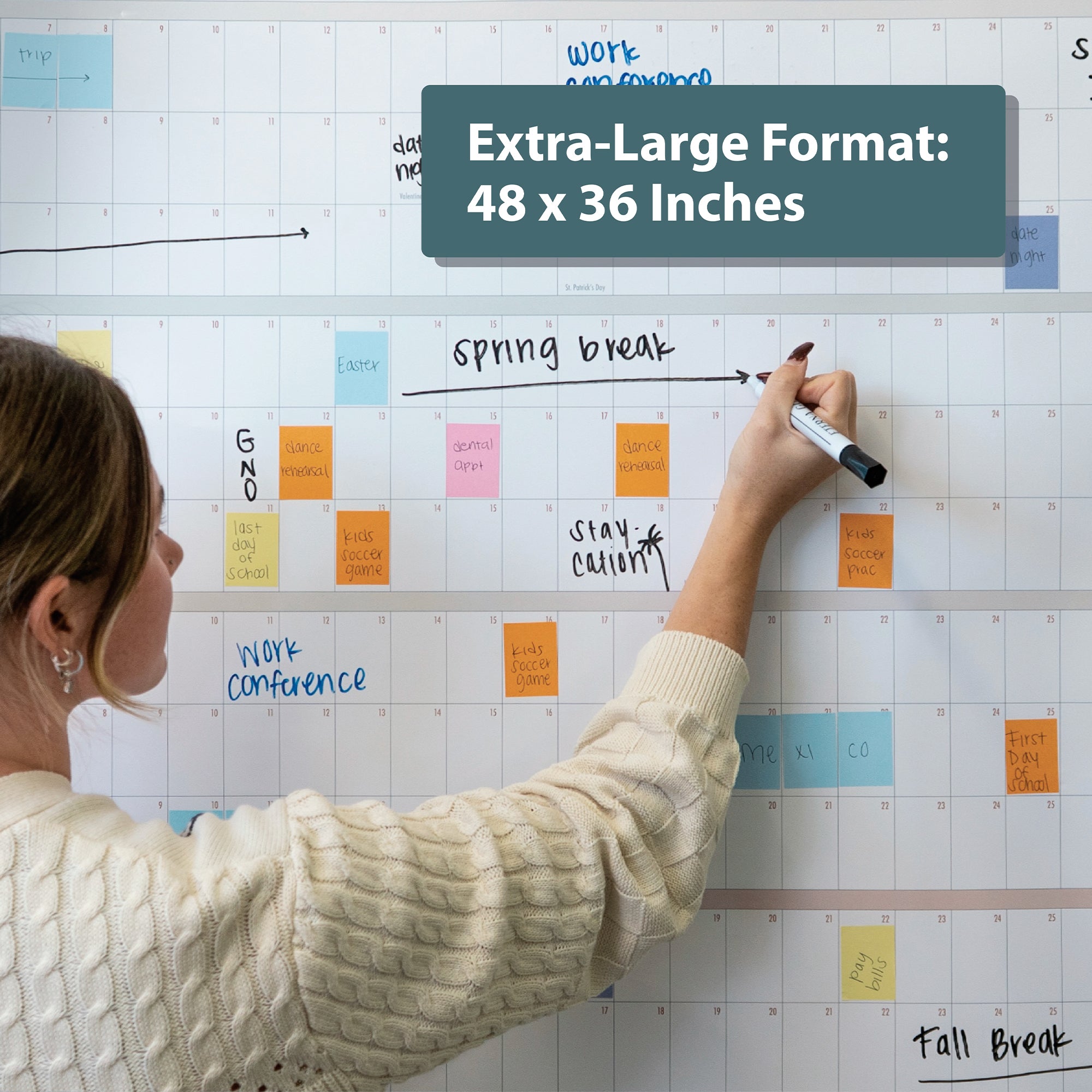 A person writes on the Eterna Goods Own the Year UNDATED GIANT Dry Erase Wall Calendar (4ft x 3ft), filled with colorful sticky notes; a label reads, "Full Year Planner—ideal for organizing your year.