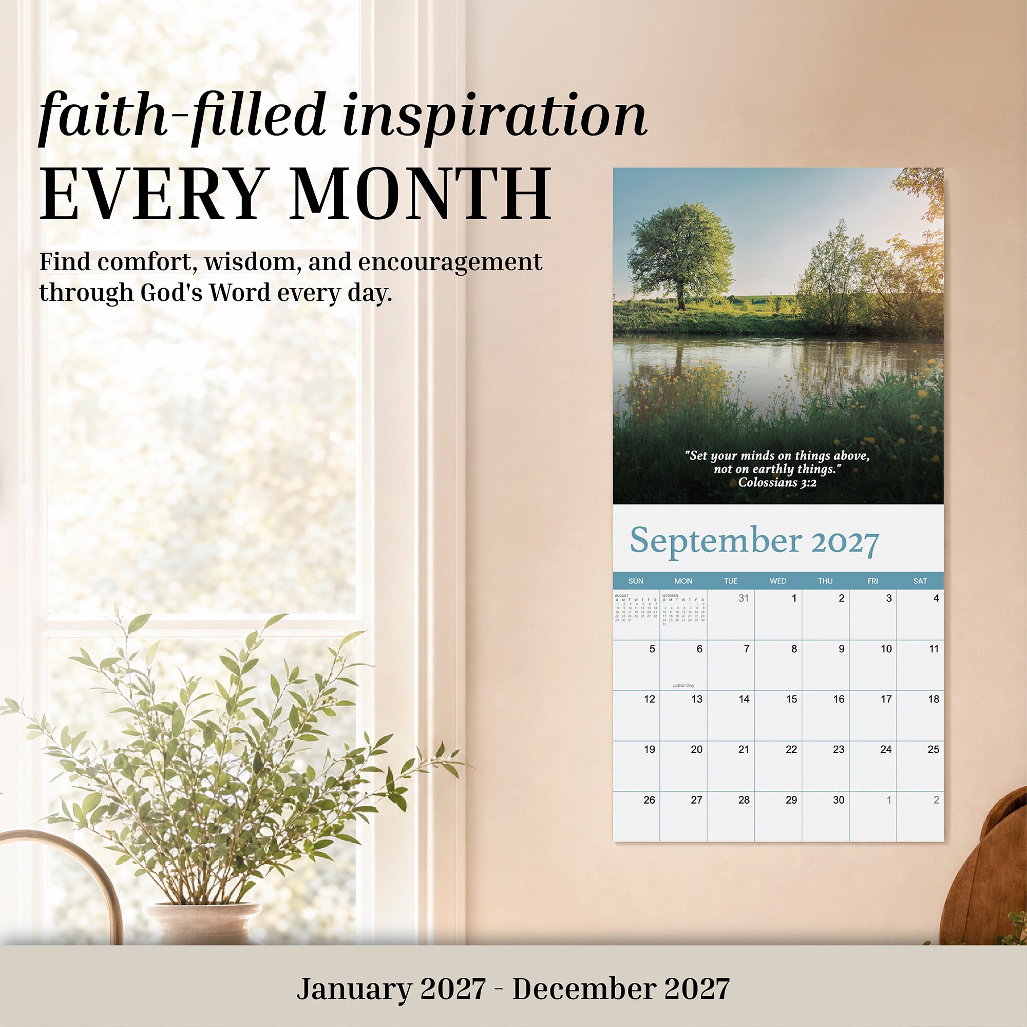 A 2027 Bible Verse Wall Calendar by Hannah Faith, open to September 2027, hangs above a small plant near a window; this Christian calendar showcases an inspiring Bible verse along with a scenic nature photograph.