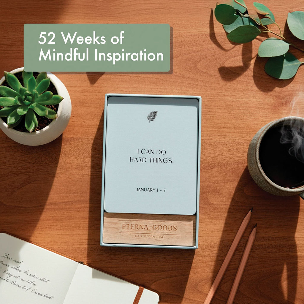 The Eterna Goods Positive Affirmation Cards Weekly Calendar sits on a desk with a card reading "I CAN DO HARD THINGS. JANUARY 1-7," beside a succulent, coffee, open notebook, and pencils—an inspiring self-care gift for mindfulness all year.