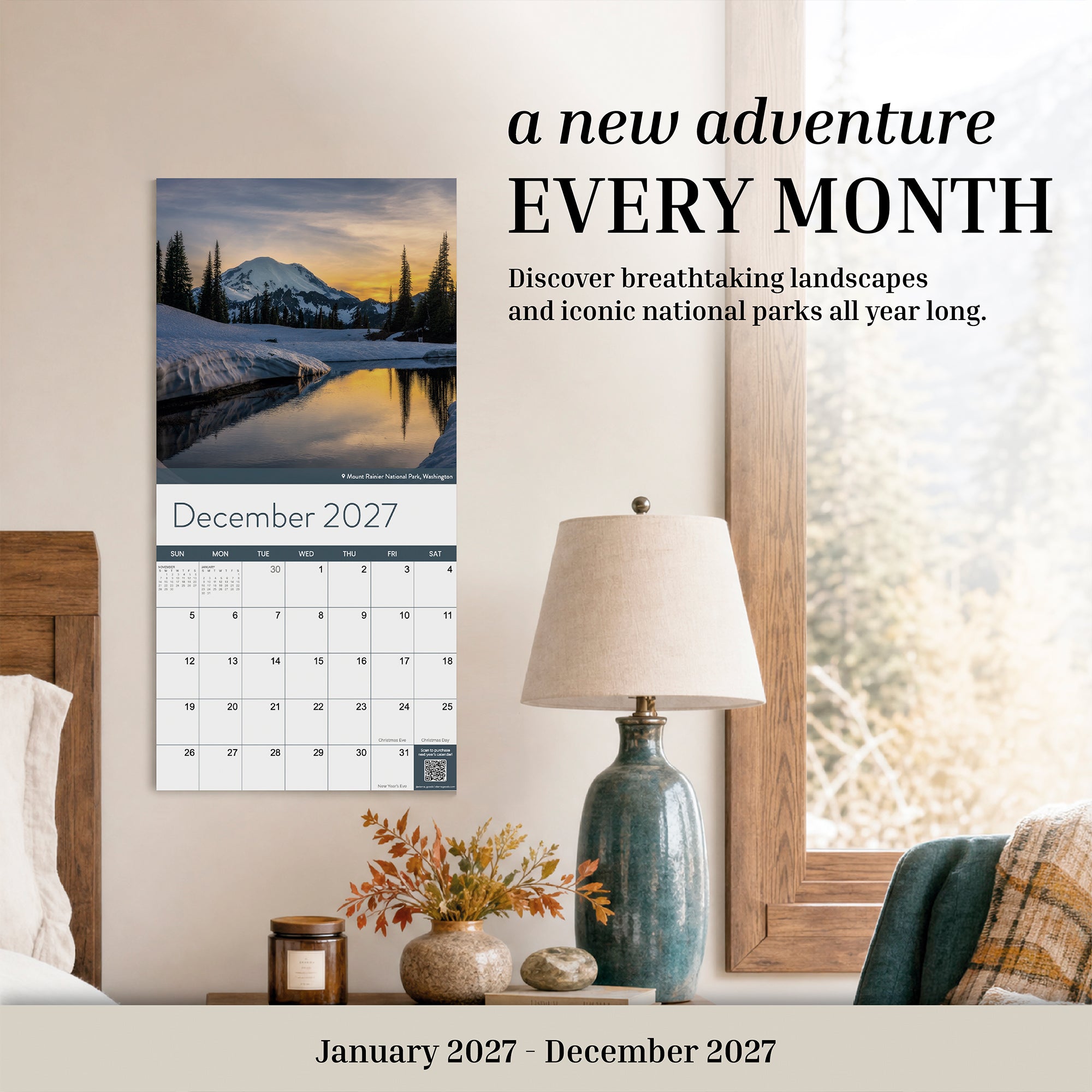 The Eterna Goods 2027 National Parks Wall Calendar hangs above a lamp and a table with a plant, showcasing breathtaking national park landscapes each month to inspire outdoor enthusiasts throughout the year.