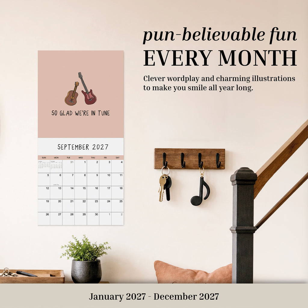 A 2027 Pun Wall Calendar by rockdoodles, featuring guitars and the phrase "So glad we're in tune," hangs above a coat rack and staircase in a modern home entryway, making it the perfect funny calendar gift for pun lovers.