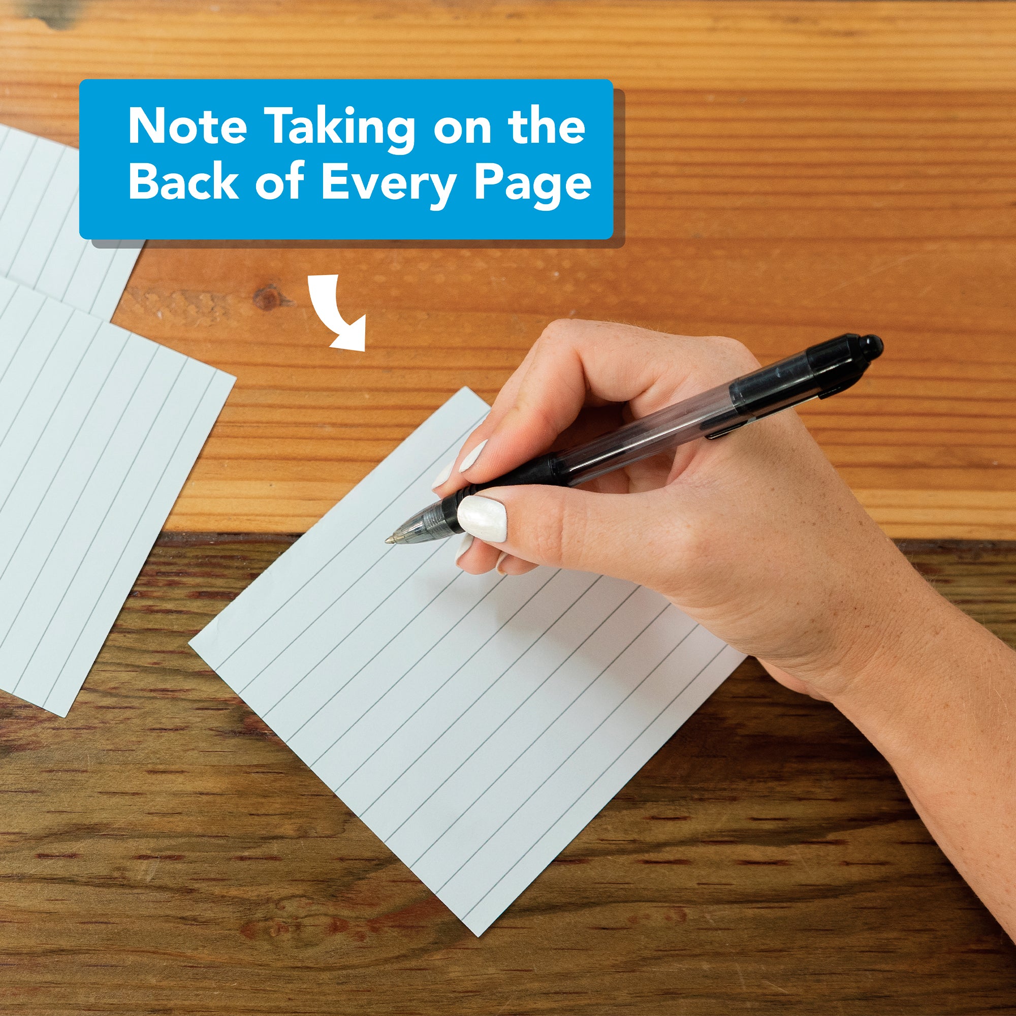 A hand writes on a lined index card with a black pen; above, a sign reads “Note Taking on the Back of Every Page”—a clever way to reuse tear-off pages from Eterna Goods’ 2026 Epic Facts Calendar as sustainable desk accessories.