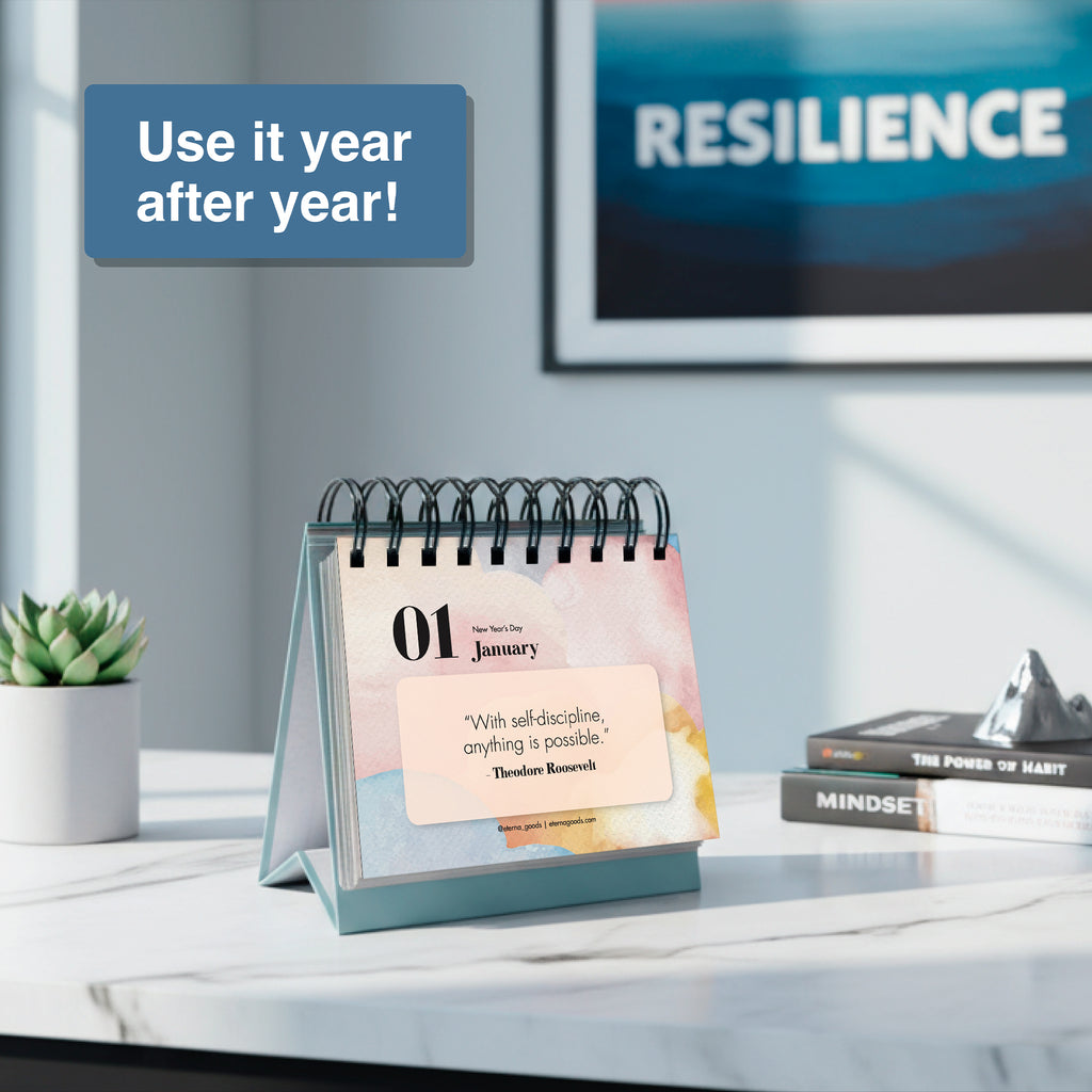 The Eterna Goods Motivational Perpetual Calendar sits on a table open to "01 January" with an inspiring quote, beside books titled "MINDSET" and "RESILIENCE." The box says, “Use it year after year!”.