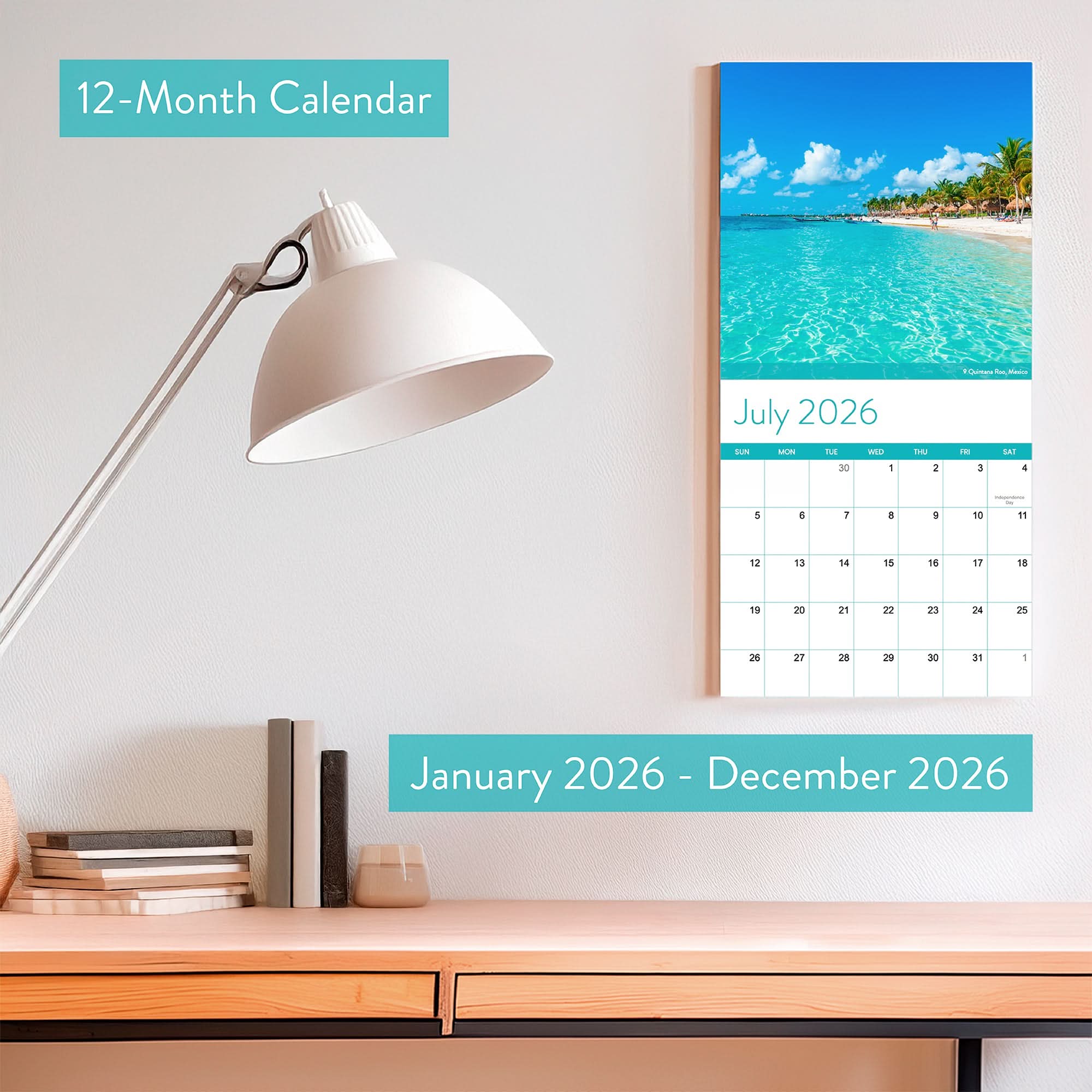 The 2026 Beaches Wall Calendar by Eterna Goods hangs above a desk with books and a lamp; its July page displays stunning coastal photography, bringing a relaxing beach vibe to your workspace.