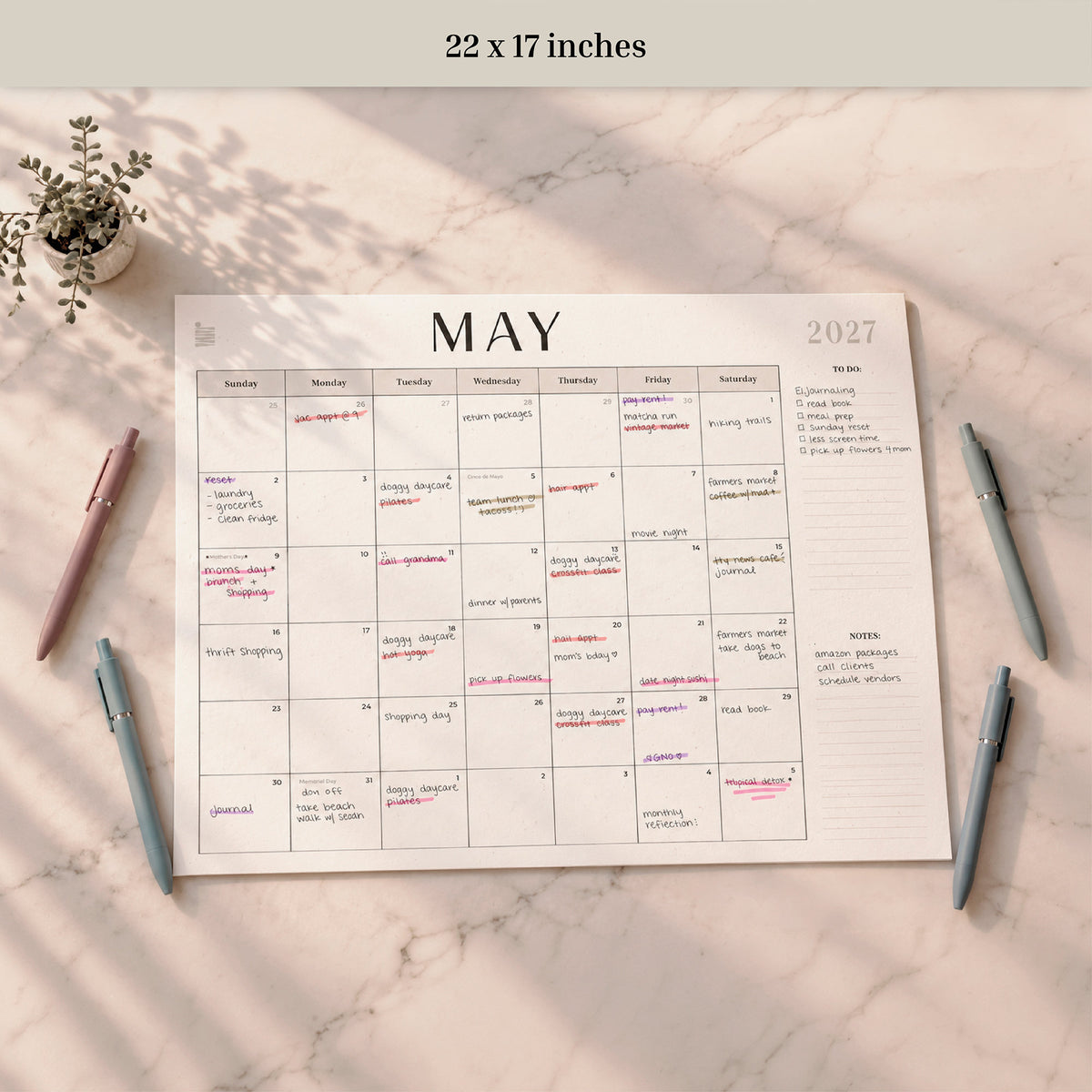 2027 12-Month Flat Desk Calendar, 22 x 17 inches, May page filled in with pens nearby