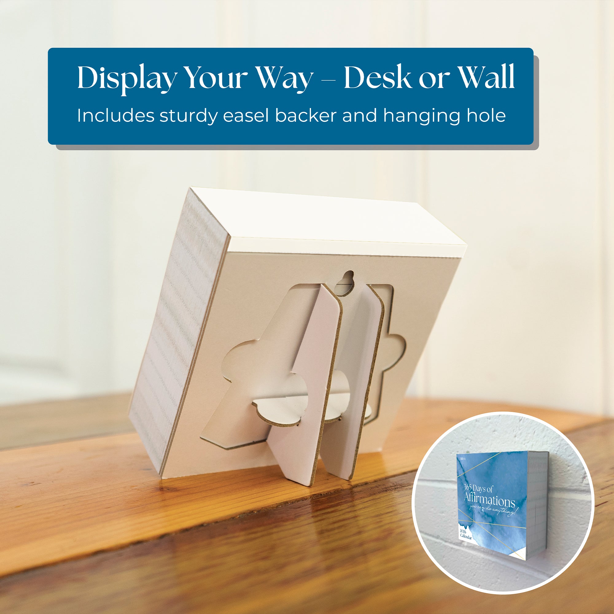 The 2026 Daily Affirmations Calendar by Eterna Goods is shown on a wooden desk with its fold-out easel and also hanging on a wall, illustrating versatile display options for desk or wall use.