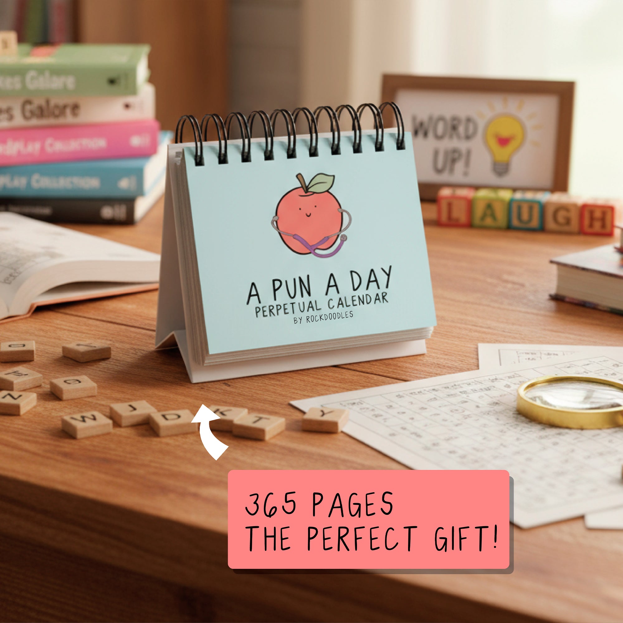 The "A Pun A Day Perpetual Calendar" by rockdoodles is a spiral-bound desk calendar, pictured with books and word games—a fun daily pun gift perfect for wordplay lovers.