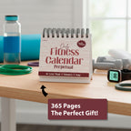 The Perpetual Fitness Calendar by Eterna Goods sits on a table surrounded by a water bottle, fitness tracker, and accessories—ideal for daily fitness tips and extra motivation.
