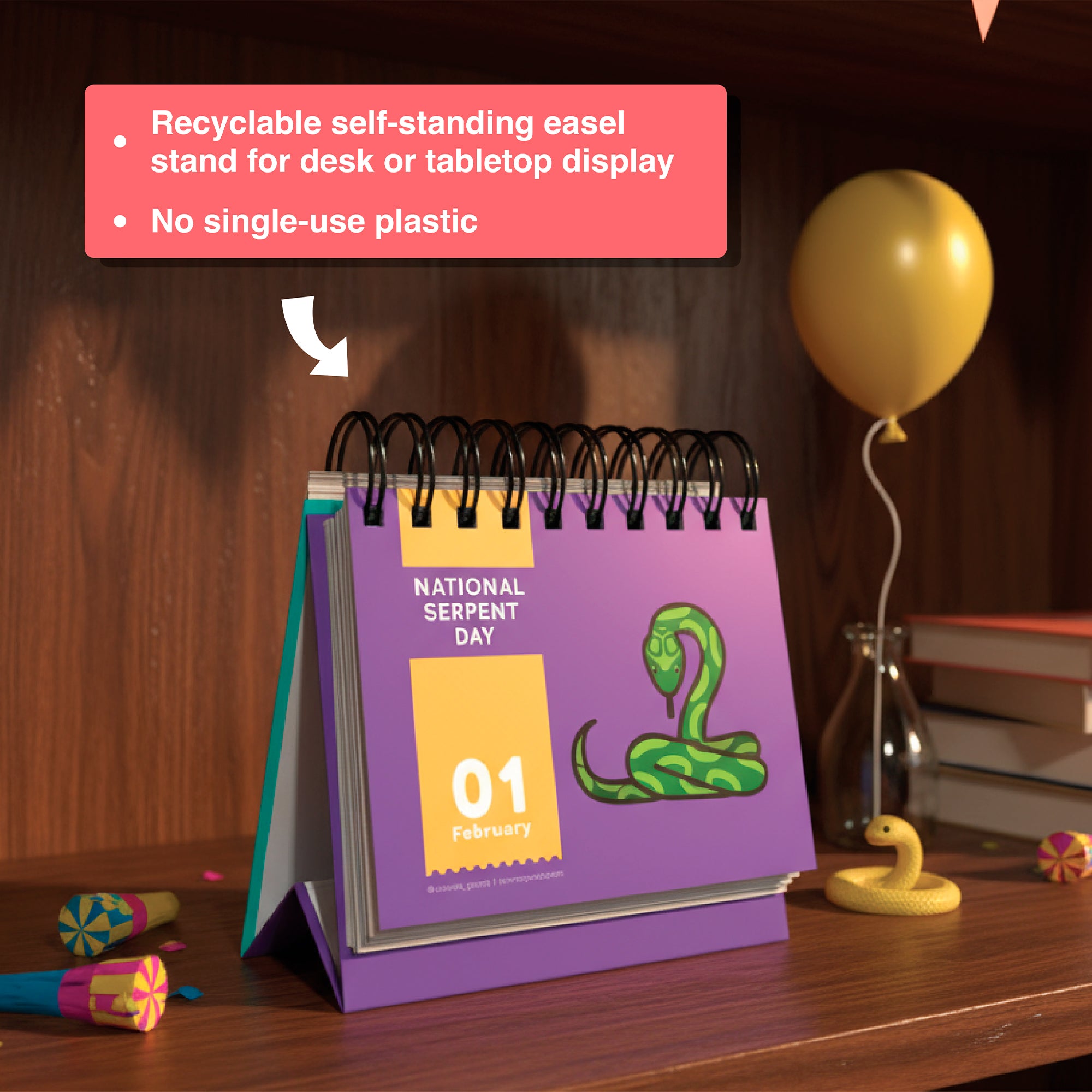 A Holiday Everyday Perpetual Calendar by Eterna Goods, open to February 1st for "National Serpent Day" with a snake illustration, sits on a wooden shelf with party items—perfect for tracking unique holidays year-round.