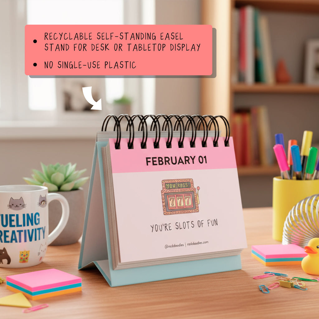 The rockdoodles A Pun A Day Perpetual Calendar sits on a desk with books, stationery, and a mug. Enjoy daily puns and eco-friendly design—recyclable easel, no single-use plastic. The perfect witty gift for any workspace!.