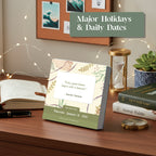 On a desk sits Eterna Goods’ 2026 Motivational Calendar showing January 1 with a Harriet Tubman quote, alongside an open notebook, pen, plant, candle, and books—including "Atomic Habits.