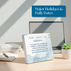The Eterna Goods 2026 Daily Affirmations Calendar, featuring "Enoch’s Birthday" and a motivational quote, sits on a desk with a laptop, notebook, pen, and potted plant in a brightly lit office.