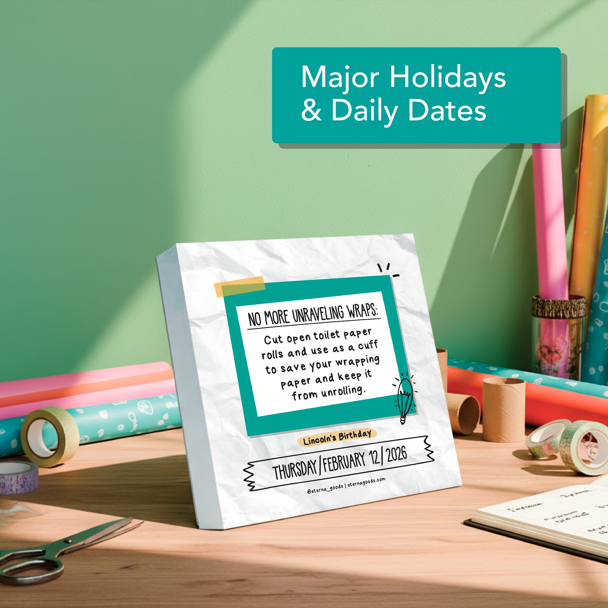 The 2026 Daily Life Hacks Calendar by Eterna Goods sits on a desk, displaying a tip for using toilet paper rolls to store wrapping paper and highlighting Lincoln’s Birthday on February 12—a smart gift for fans of clever organization.