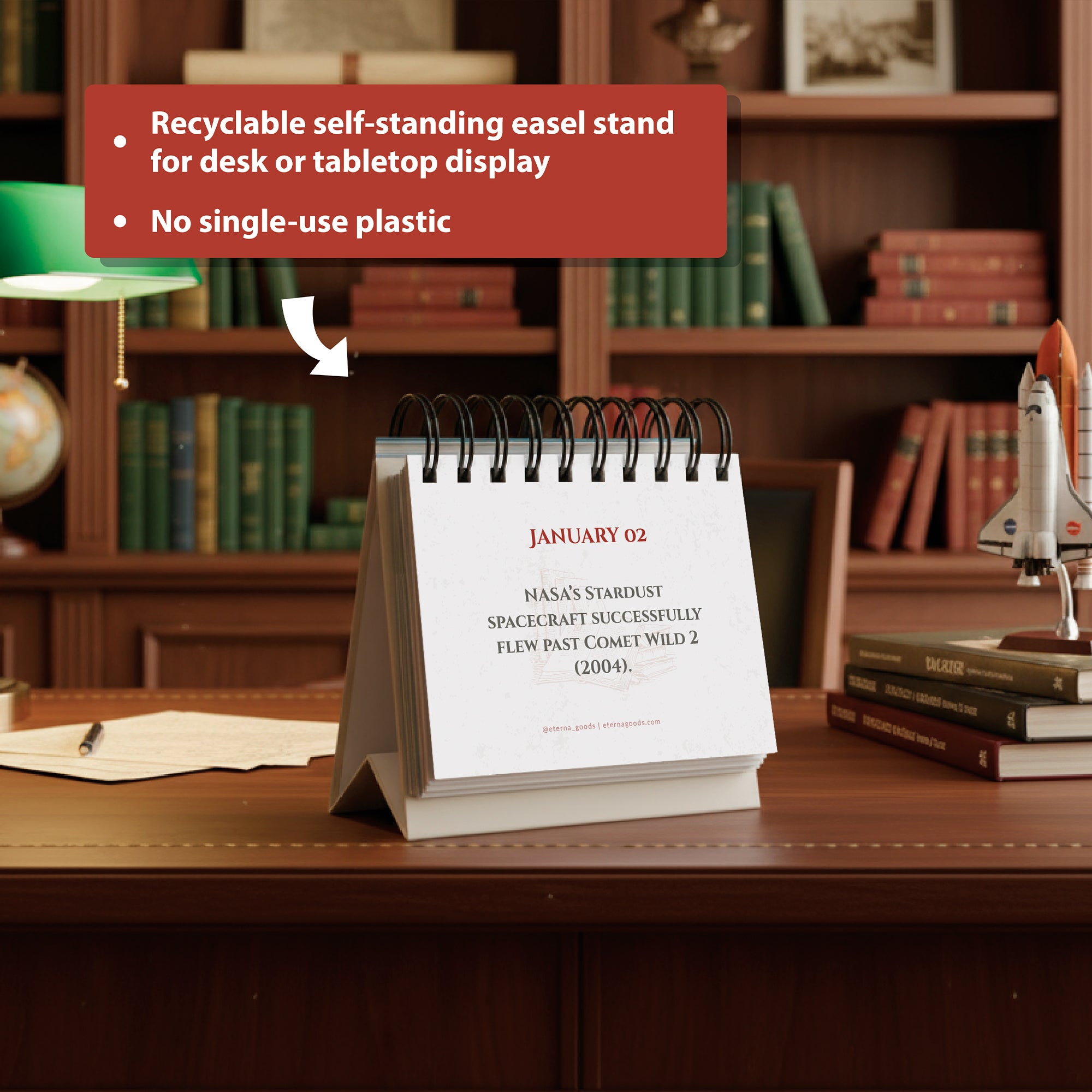 The Eterna Goods Today In History Perpetual Calendar, featuring daily historical facts and a recyclable easel, sits on a wooden desk. A bookcase and model space shuttle nearby make it an ideal educational gift for any workspace.