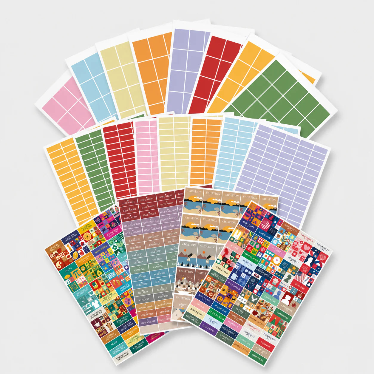The Own The Year Sticker Bundle by Eterna Goods features vibrant rectangular planning block stickers and illustrated sheets, arranged in a fan-like display on a white surface.