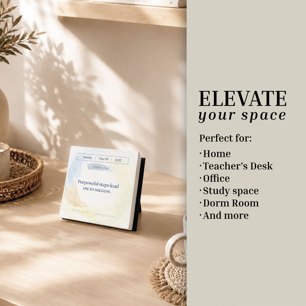 The 2027 Daily Affirmations Calendar by Eterna Goods stands on a wooden table beside a plant, featuring text that highlights its suitability for spaces such as the home, teacher’s desk, office, study area, dorm room, and more—perfect for inspiring mindfulness and daily positive affirmations.