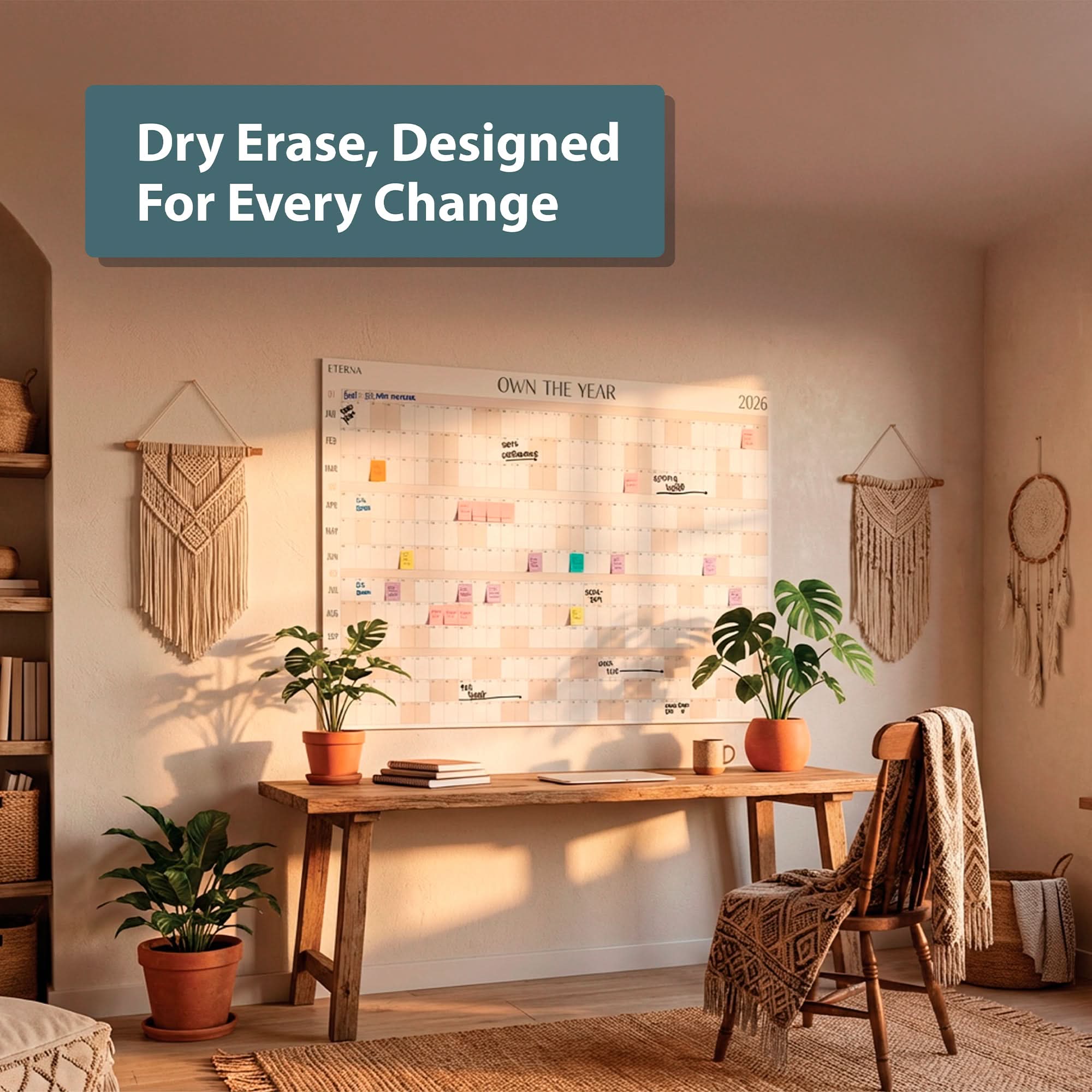 Home office featuring the Own The Year Calendar by Eterna Goods—a giant dry erase wall calendar—plus a wooden desk, plants, and boho decor. Text overlay reads, “Dry Erase, Designed For Every Change.”.