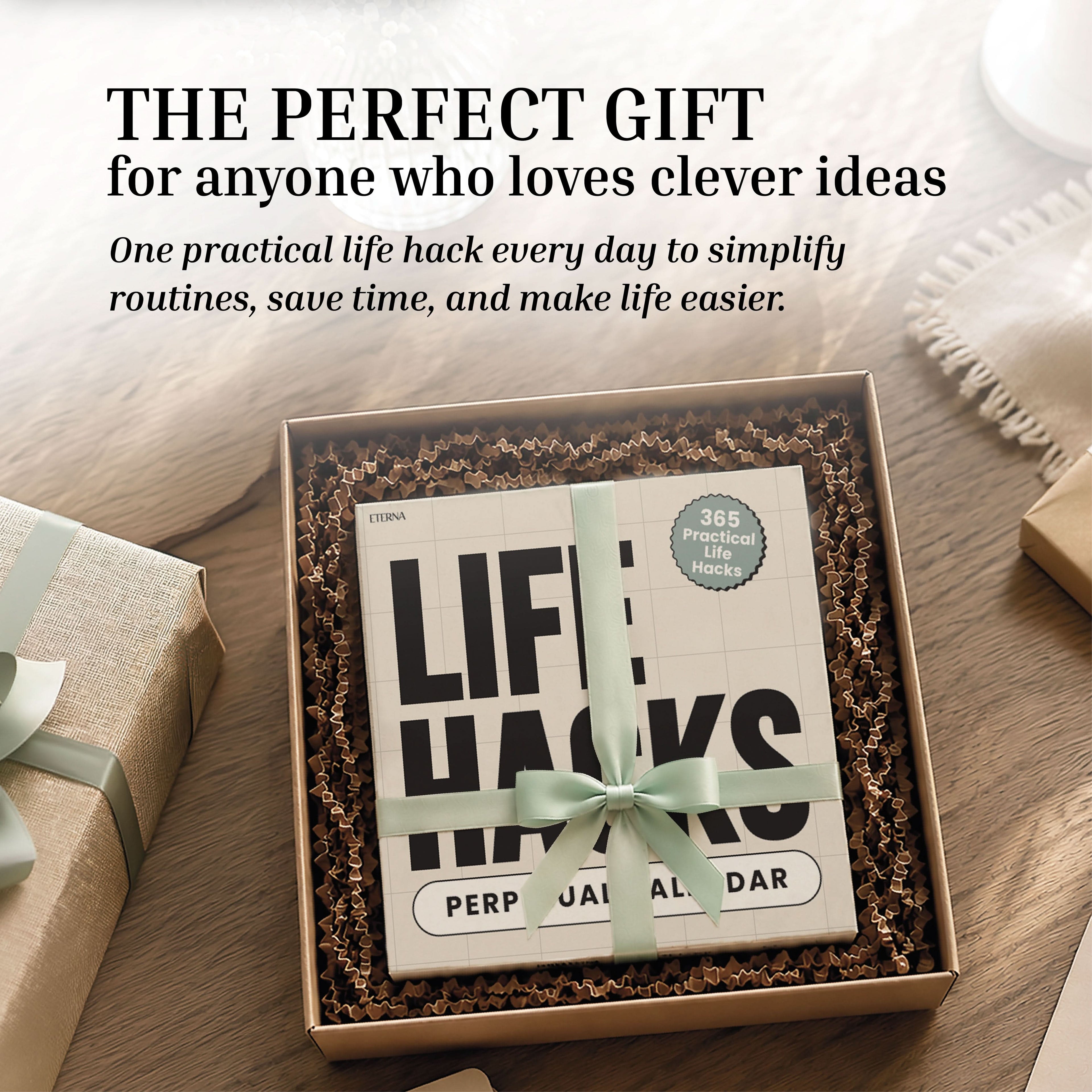 A boxed Perpetual Life Hacks Calendar from Eterna Goods, labeled with "LIFE HACKS" and tied with a green ribbon, rests on brown packing material amid wrapped gifts and a cup of coffee—a stylish and practical addition to daily living.