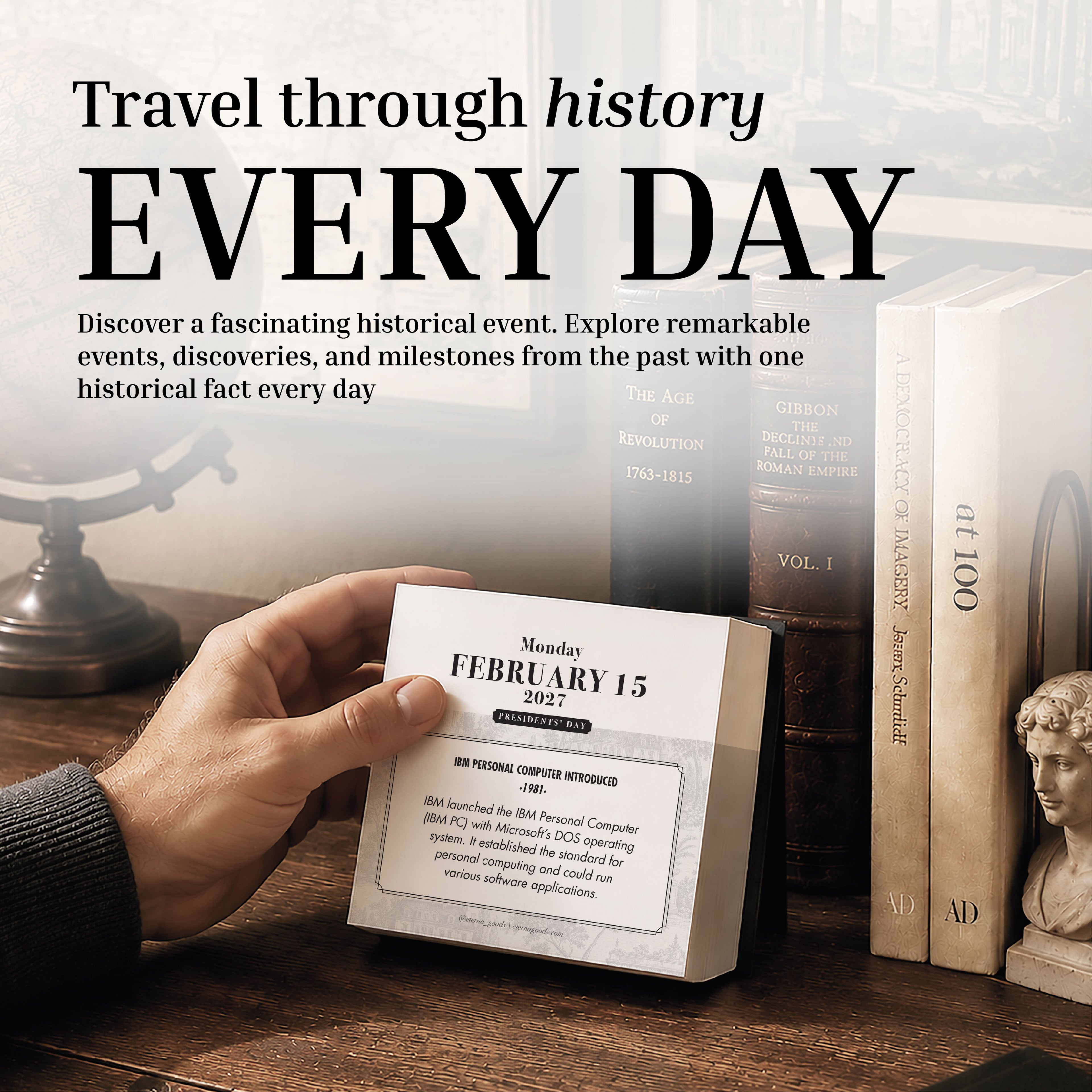 A hand flips a page on the Eterna Goods 2027 Historical Facts Calendar, an inspirational desk calendar with tear-off pages, surrounded by classic books and a candle holder on a wooden table.
