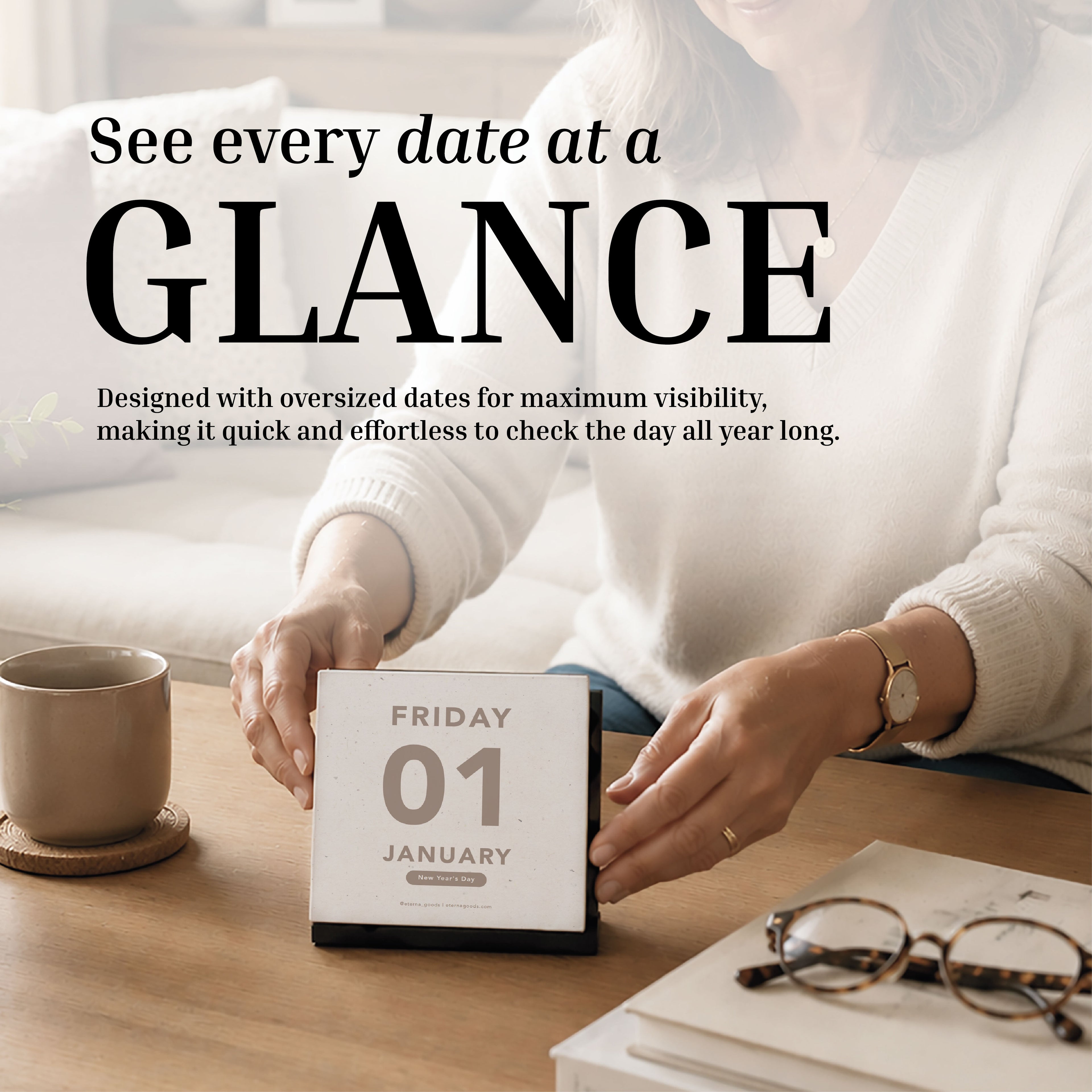 An individual flips the Eterna Goods 2027 Large Text Calendar on a wooden desk beside a mug and notebook; bold text showcases the calendar’s high visibility and easy-to-read dates.