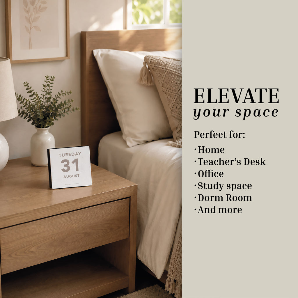 A neatly made bed beside a wooden nightstand features the Eterna Goods 2027 Large Text Calendar, with easy-to-read dates showing Tuesday, 31 August, complemented by a vase with greenery and a framed picture—promoting simple ways to elevate your space.