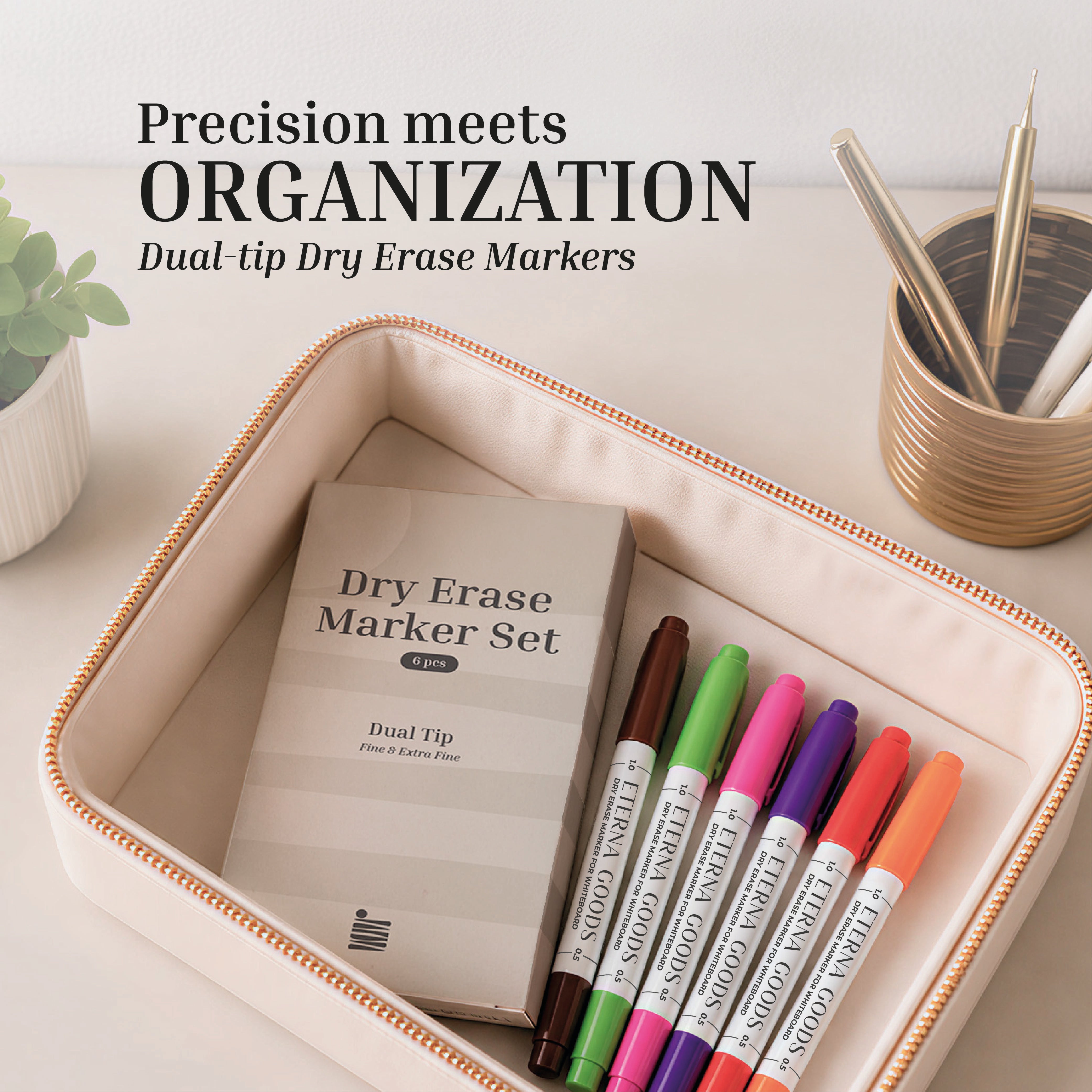 A beige box from Eterna Goods holds a Fine Tip Dry Erase Marker Set of six dual-tip markers, displayed beside a plant and pen holder. Text states: "Precision meets ORGANIZATION.