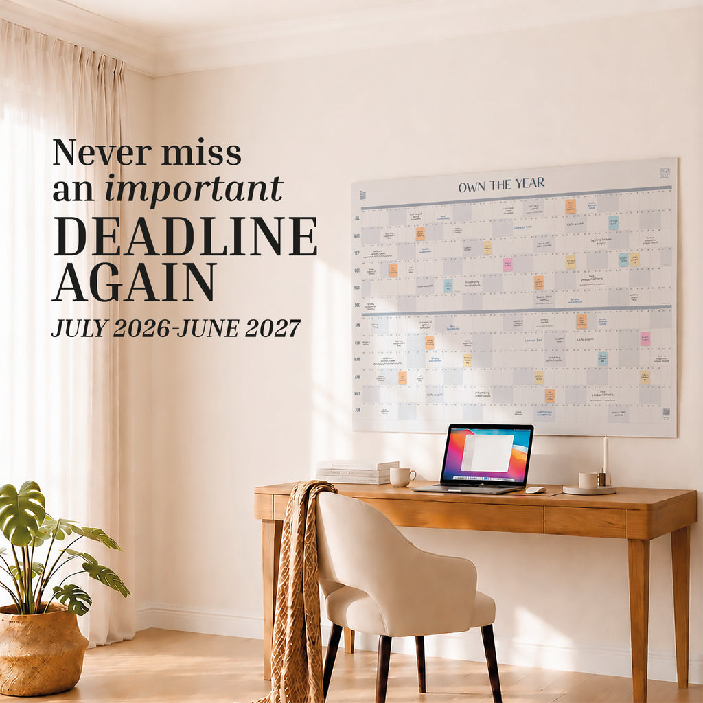 A home office with a wooden desk, chair, laptop, plant, and a large Eterna Goods 2026-2027 Midyear/Academic Own The Year Calendar. Text: "Never miss an important deadline again. July 2026–June 2027.