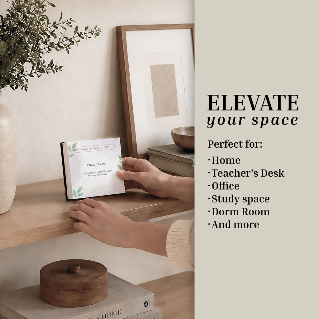 A person places the Eterna Goods 2027 Mindfulness Calendar—framed as a decorative sign—on a wooden shelf alongside books, vases, and art; text beside it suggests perfect spots to elevate your space, such as your home, office, or dorm room. These settings are ideal for daily mindfulness exercises or for displaying the calendar to inspire ongoing stress relief throughout the day.