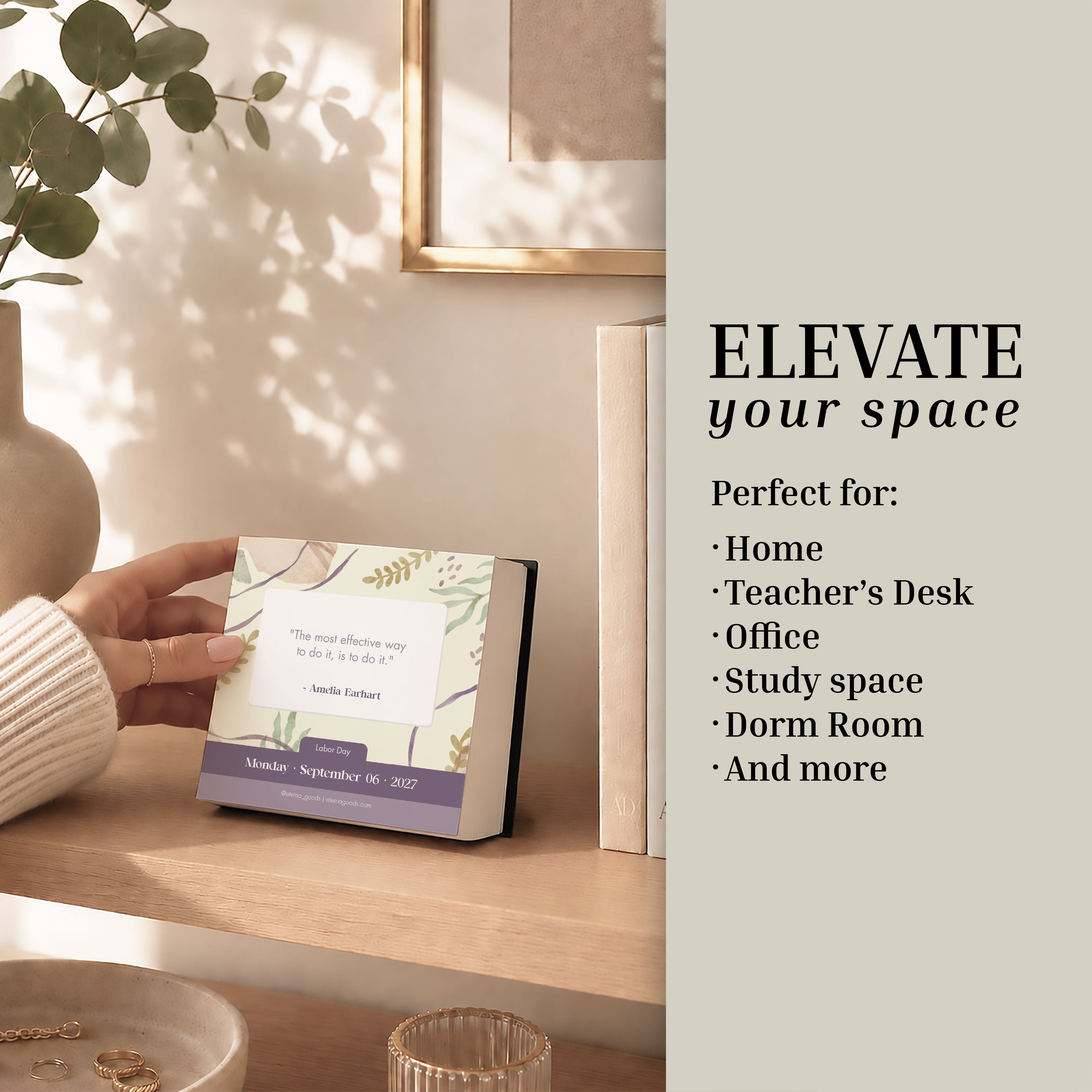 An individual sets the Eterna Goods 2027 Motivational Calendar—a desk calendar with daily inspirational quotes—on a light wood shelf alongside a plant, framed photo, and books; accompanying text highlights that this tear-off calendar from Eterna Goods is perfect for spaces such as the home, office, and desk.
