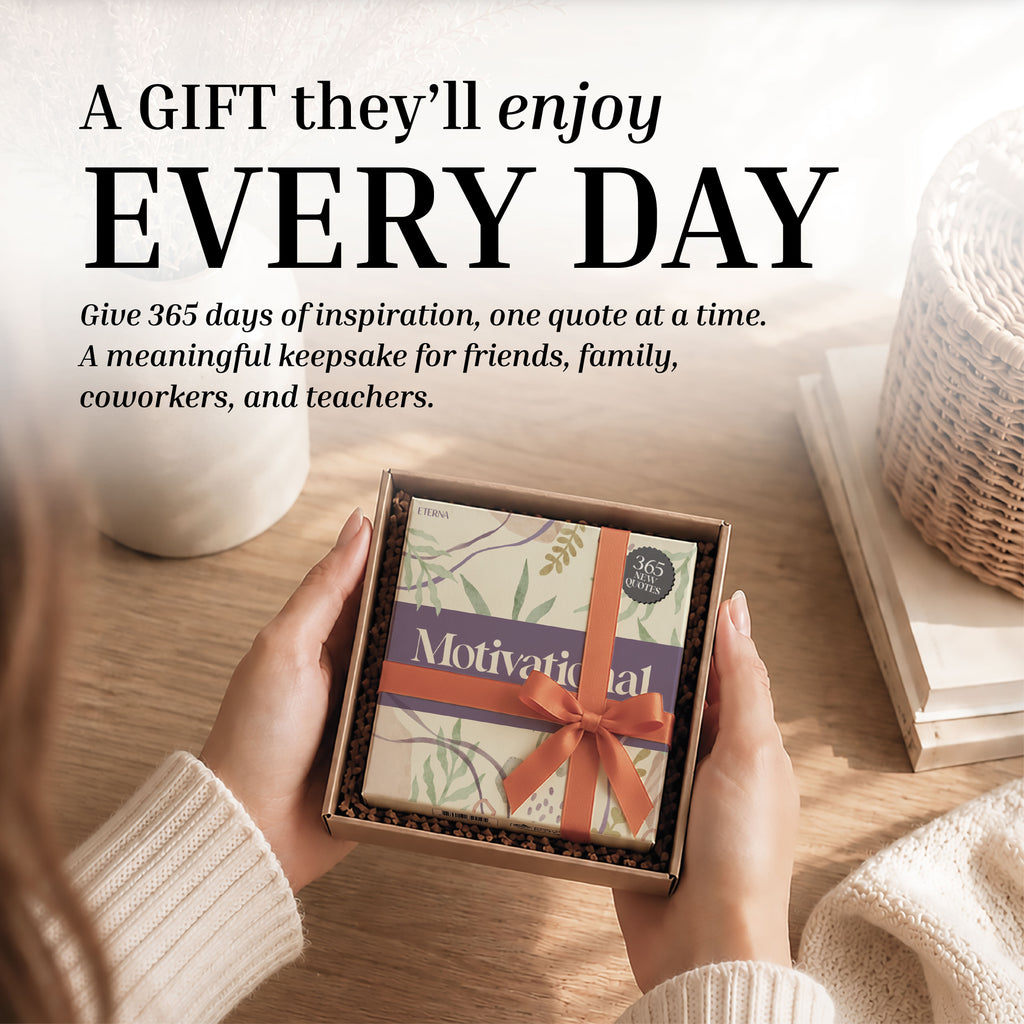 Hands holding a boxed "2027 Motivational Calendar" gift from Eterna Goods, wrapped with a ribbon, on a table beside a basket and a cup. This thoughtful present doubles as an inspirational desk calendar, featuring daily motivational quotes in an easy tear-off format—perfect for friends, family, coworkers, and teachers seeking encouragement each day.
