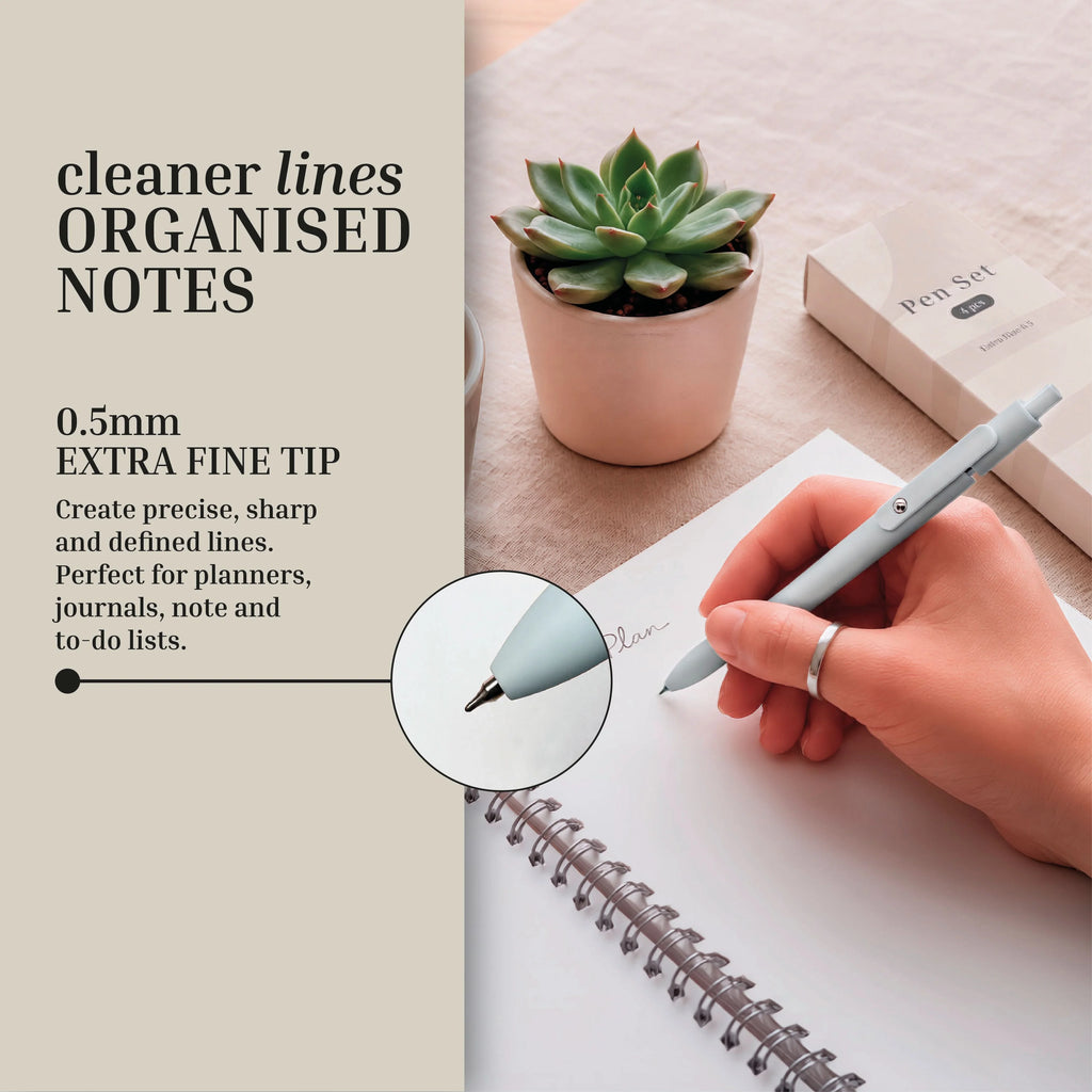 An individual writes in a spiral notebook with a sleek grey pen beside a succulent plant, highlighting the pen’s 0.5mm extra fine tip for precise and tidy notes—making it a perfect part of the Eterna Goods Planning Essentials Kit for anyone who values smooth, fine-tip writing tools.