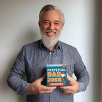 A smiling man with gray hair and beard holds the Eterna Goods Perpetual Dad Joke Calendar, featuring full-color art, against a plain white background.
