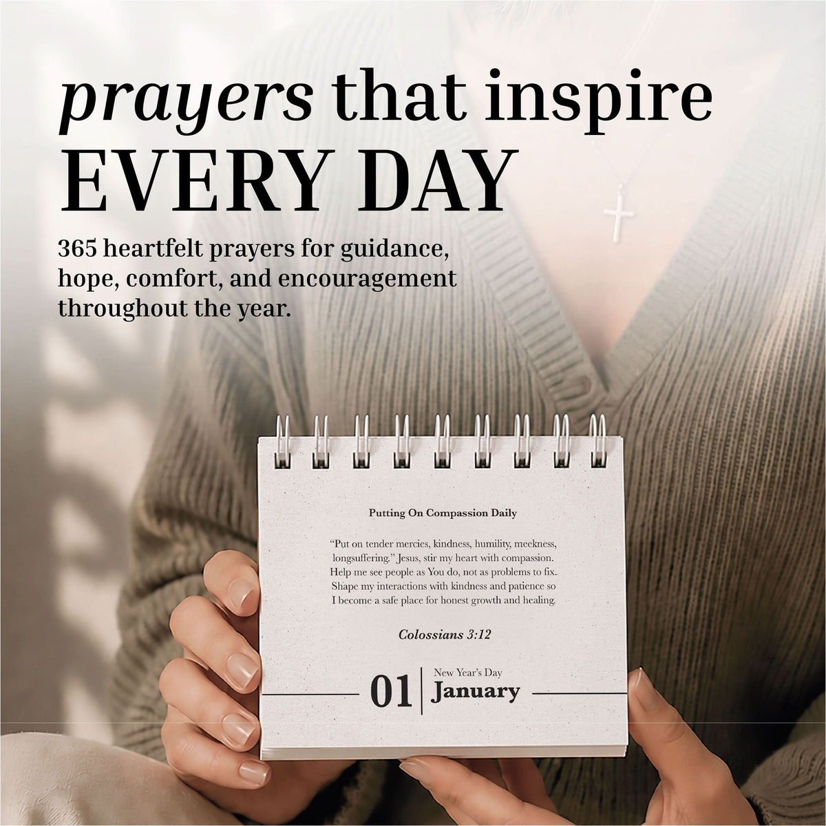 A person holds the Eterna Goods Perpetual Prayer A Day Calendar, a compact spiral-bound calendar featuring January 1, with a cross necklace in view and uplifting prayers from the calendar visible in the background.