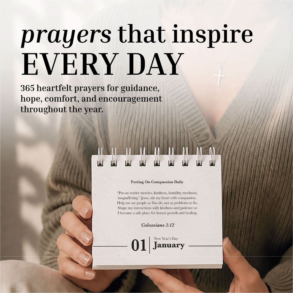 A person holds the Eterna Goods Perpetual Prayer A Day Calendar, a compact spiral-bound calendar featuring January 1, with a cross necklace in view and uplifting prayers from the calendar visible in the background.