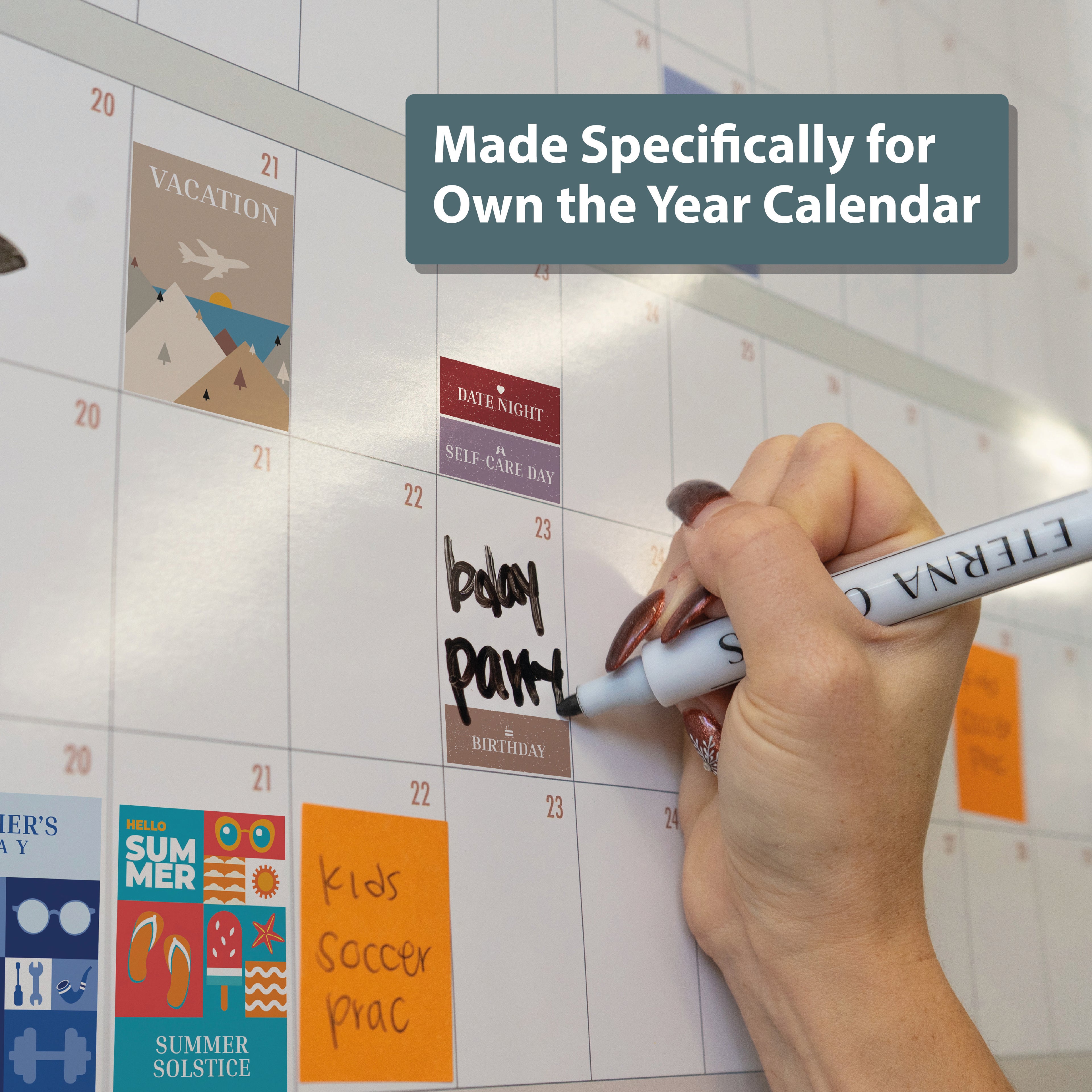 A hand writes "bday party" on an Own the Year wall calendar decorated with Eterna Goods' Holiday Stickers Pack; text overlay says, "Made Specifically for Own the Year Calendar.