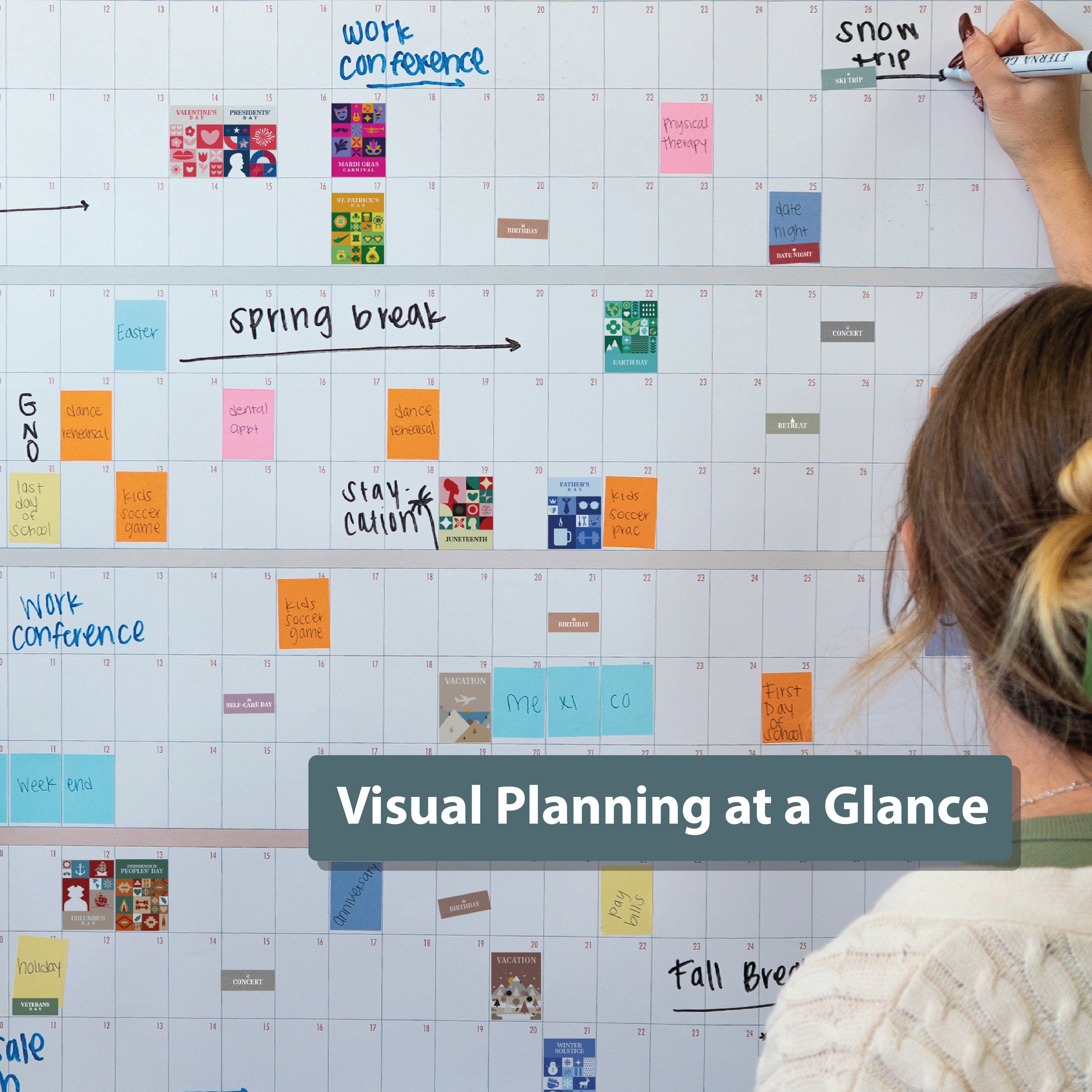 A person writes on an Eterna Goods wall calendar, decorated with vibrant Own The Year Sticker Bundle notes and labels; text overlay says “Visual Planning at a Glance.”.