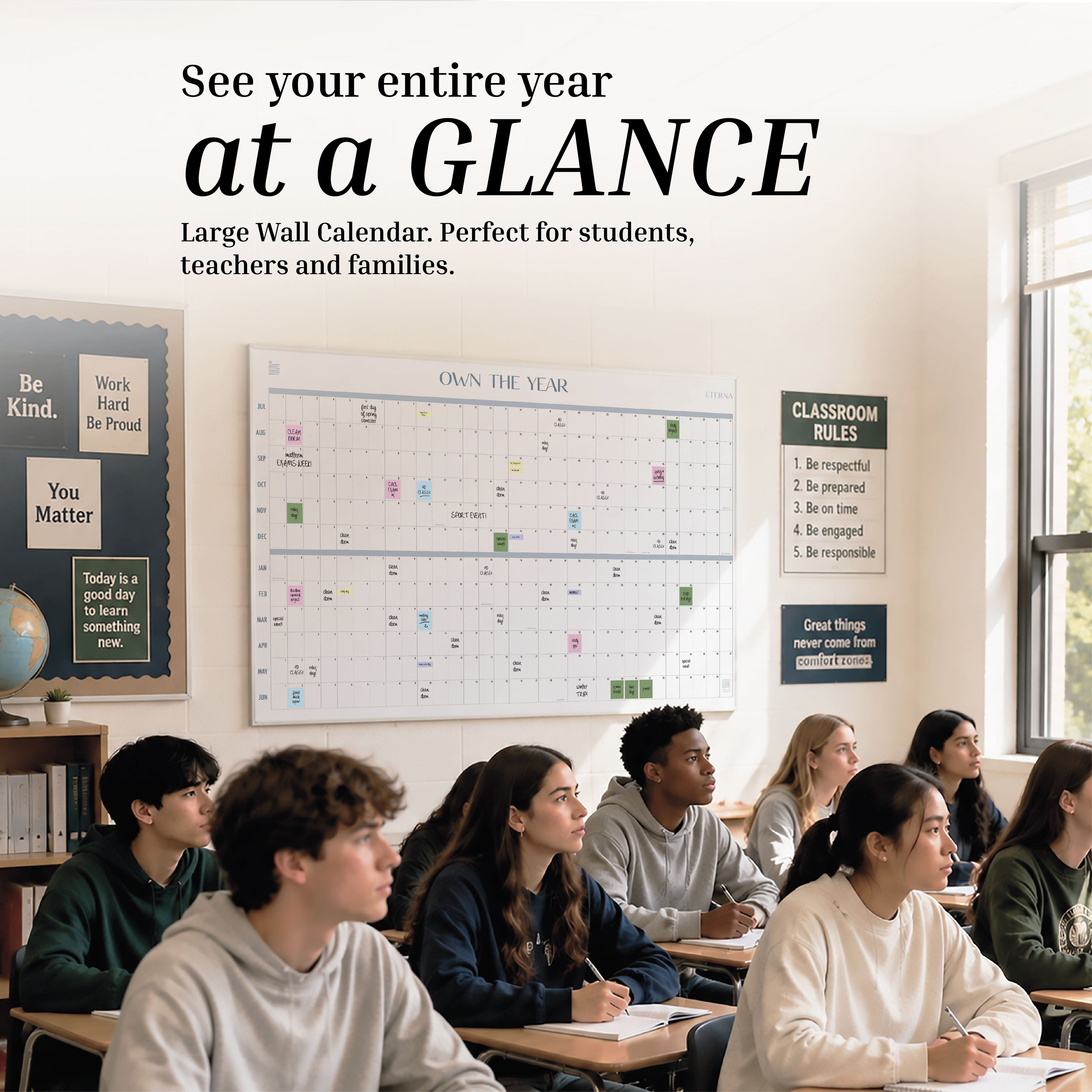 A diverse group of students sits in a classroom facing forward. On the walls, a giant dry erase wall planner is displayed alongside the Eterna Goods Undated Academic Own The Year Calendar and motivational posters.