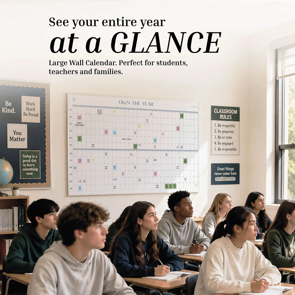 A diverse group of students sit at desks in a classroom facing forward. A large wall calendar and motivational posters are visible on the wall behind them, including the Own The Year Midyear / Academic Calendar by Eterna Goods, which helps everyone stay organized and on track throughout the school year.
