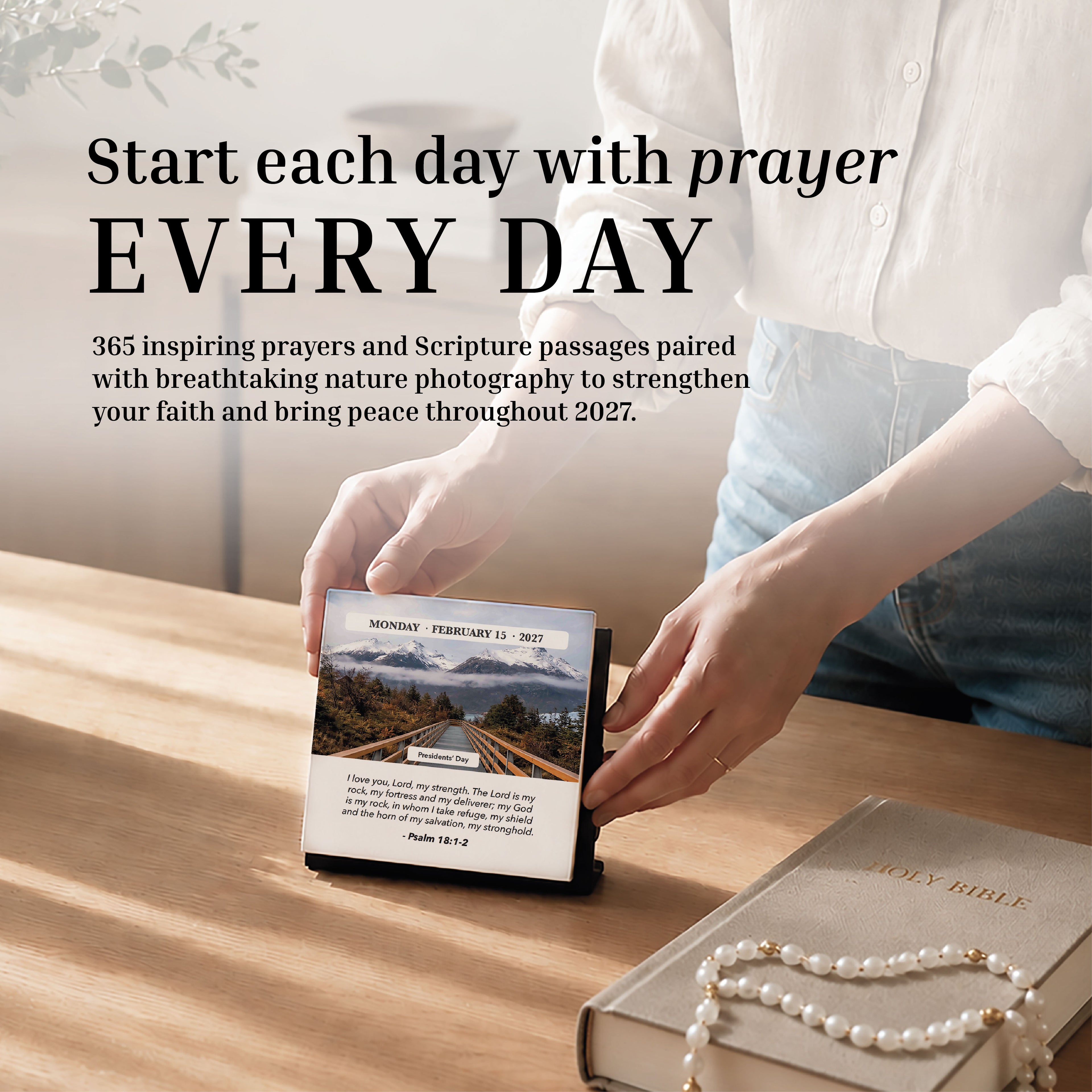 A person opens the Hannah Faith 2027 Verse A Day Calendar on a desk alongside a Holy Bible and beaded bracelet, sunlight pouring across the surface as they seek spiritual growth through daily inspirational Bible verses.