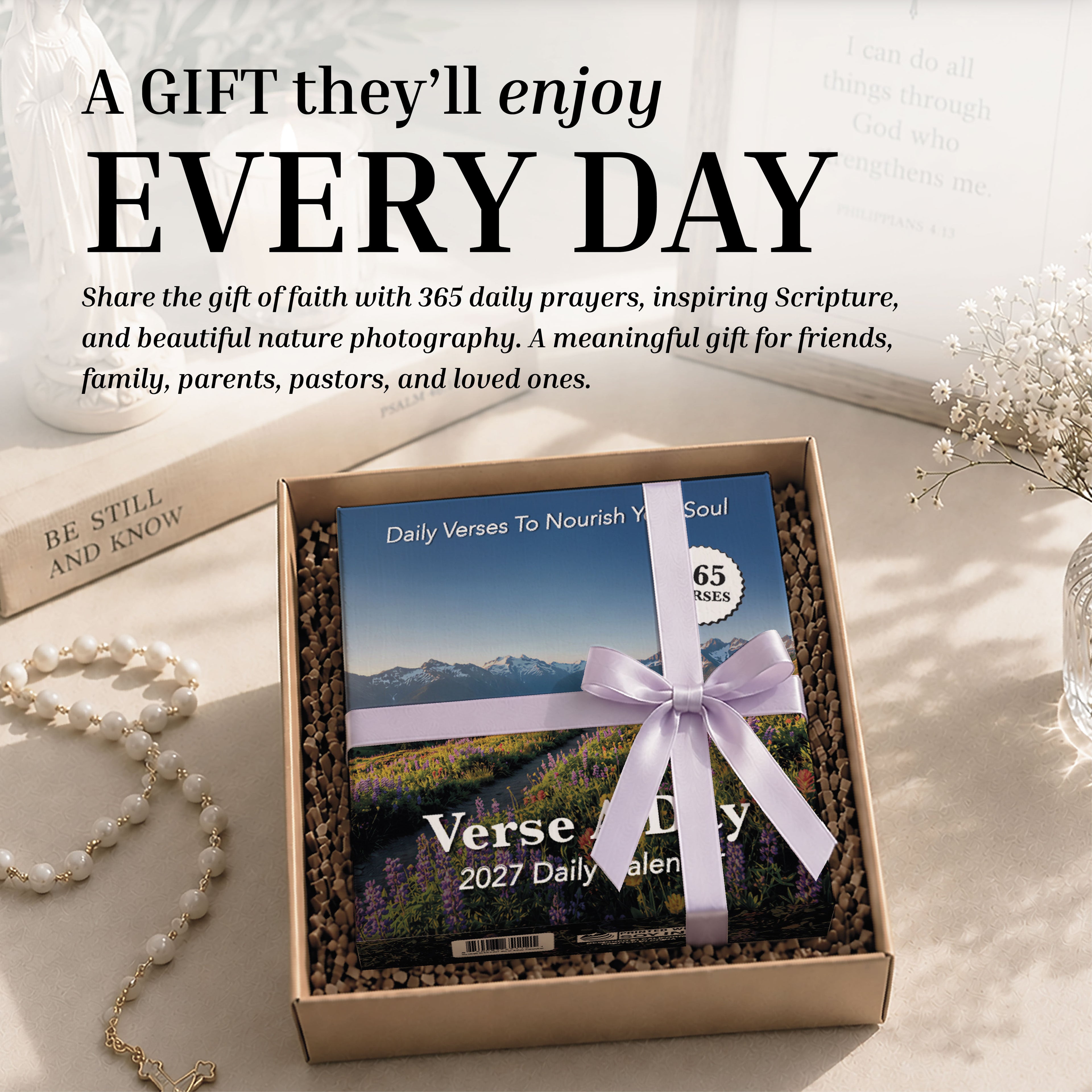 A boxed Hannah Faith 2027 Verse A Day Calendar, adorned with a lavender ribbon, rests on a table alongside a pearl necklace, a gold bracelet, and a card in the background—perfect for inspiring daily spiritual growth.
