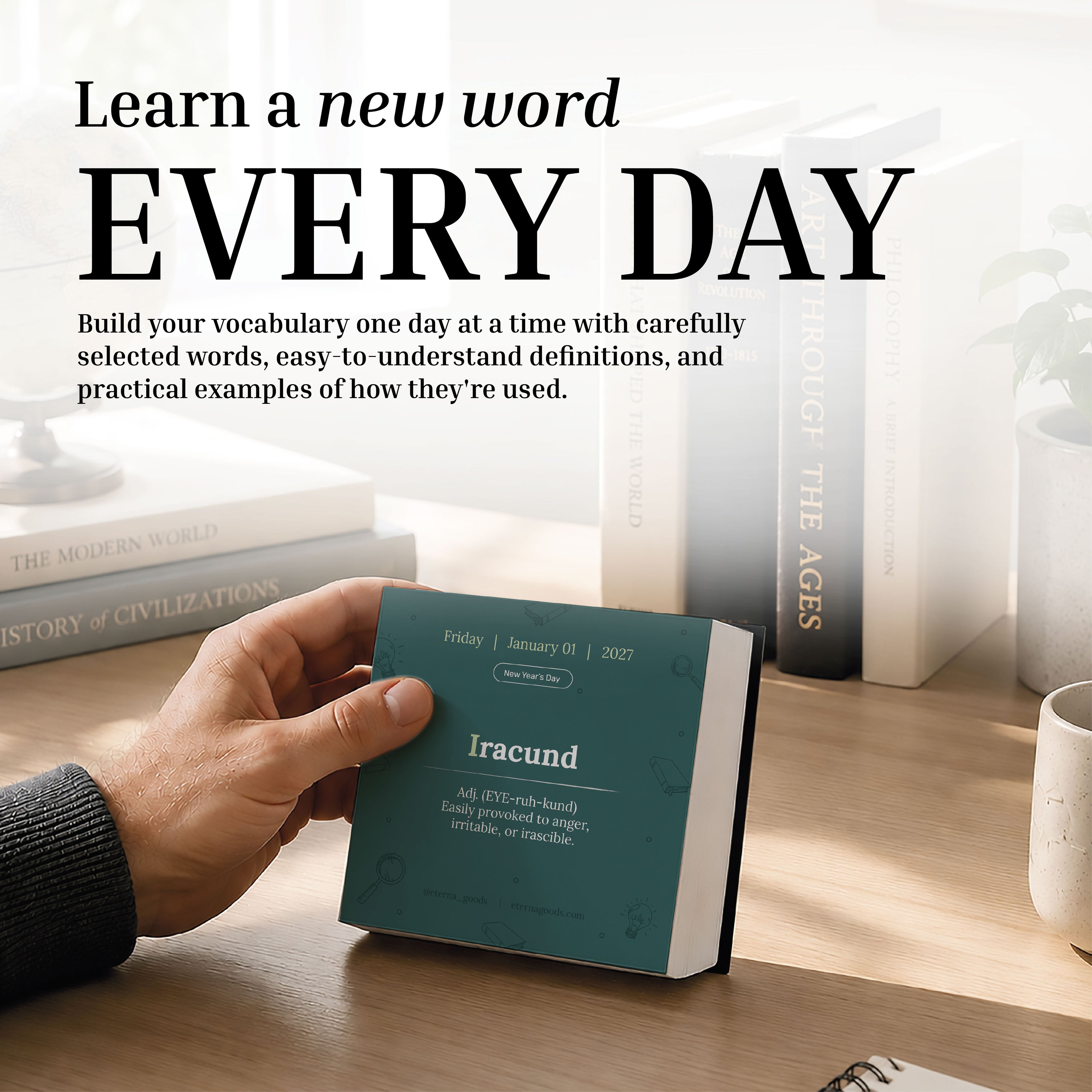 A hand holds the Eterna Goods 2027 Word Of The Day Calendar open to the word "iracund" on a desk with books and sunlight in the background, showcasing a daily vocabulary discovery experience.
