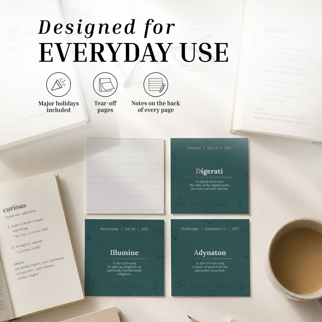 A desktop featuring books, a cup of coffee, and the Eterna Goods 2027 Word Of The Day Calendar displaying word definitions and notes, with features such as highlighted holidays, tear-off pages, and space for daily vocabulary notes.