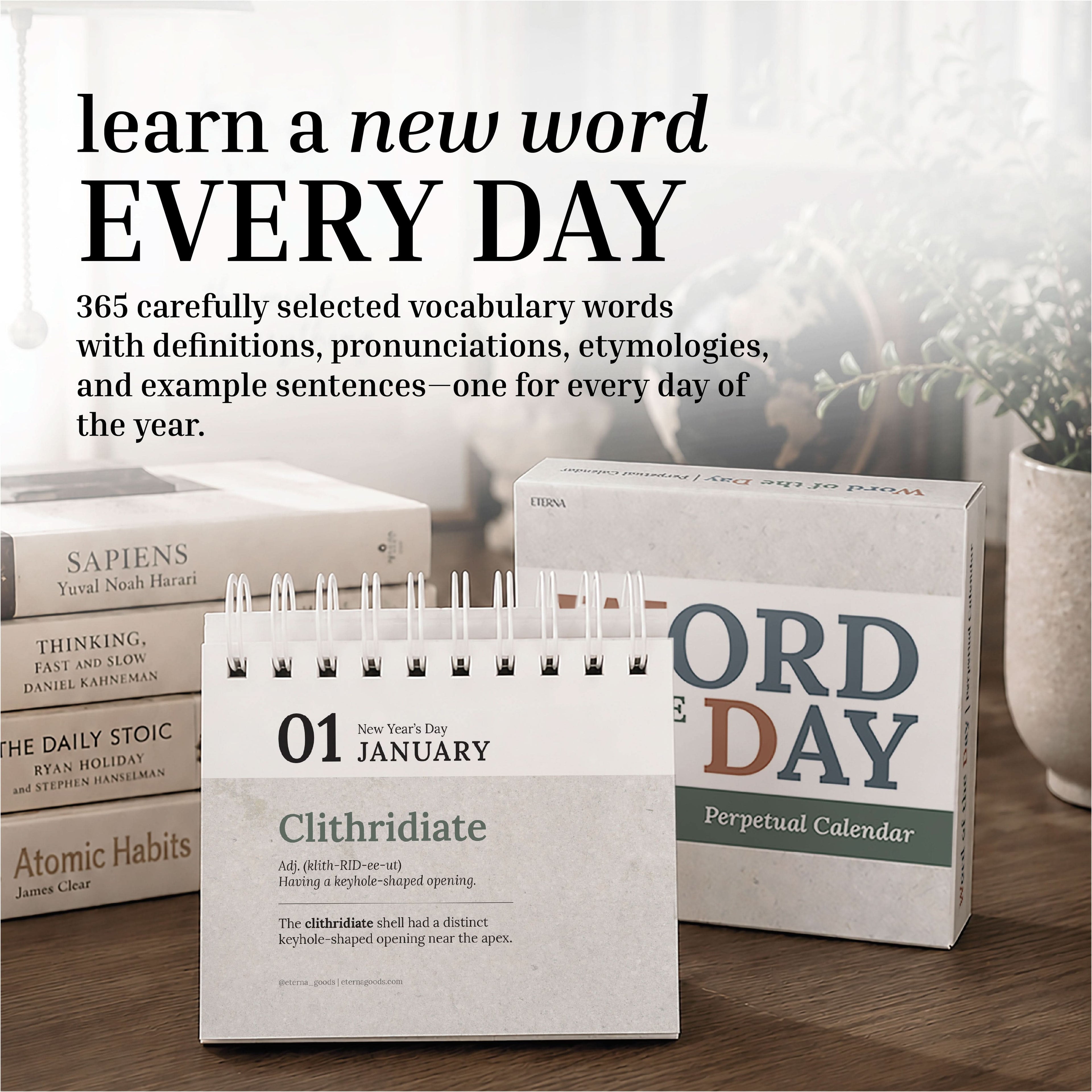 The Eterna Goods Perpetual Word of the Day Calendar sits atop a wooden surface with books stacked in the background, featuring "Clithridiate" and its definition for January 1 as a daily vocabulary builder.