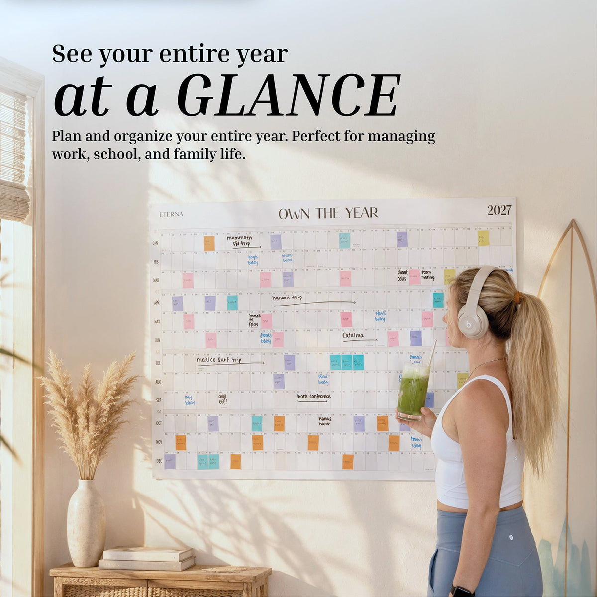 Woman looking at the 2027 Dated Own The Year Calendar on a wall, filled in with colored notes