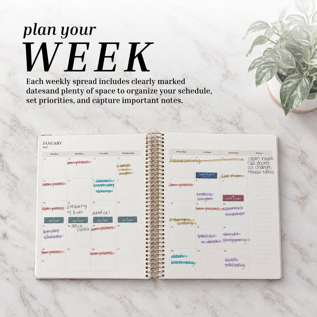 Dated Weekly Planner 2027 weekly spread filled in on a marble desk with a plant