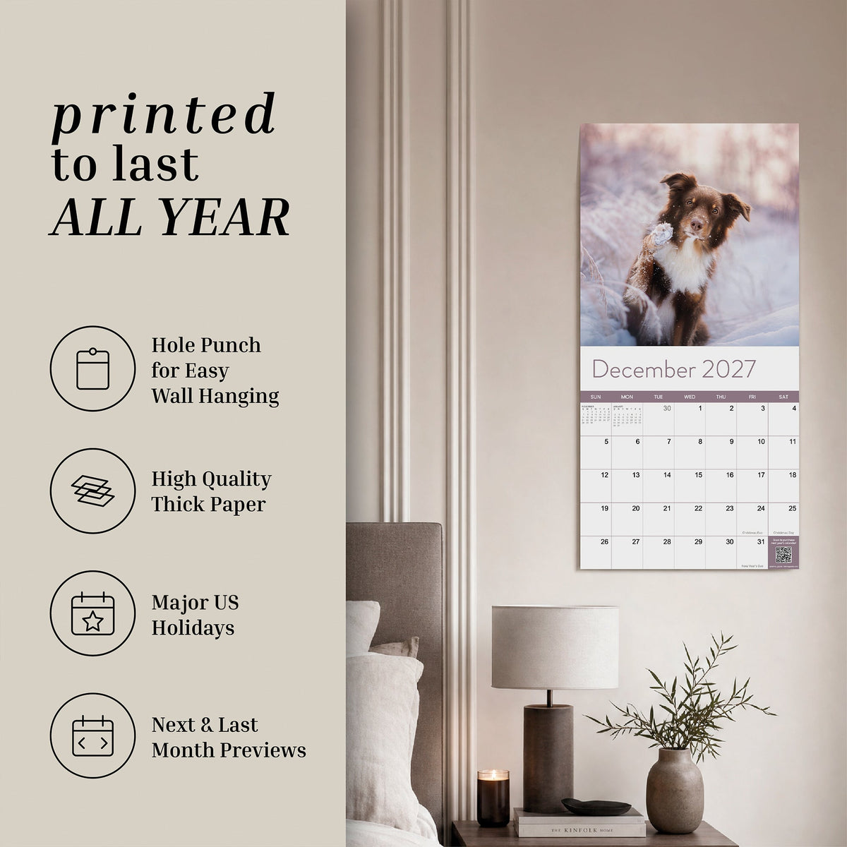 An Eterna Goods 2027 Dogs Wall Calendar, featuring vibrant monthly canine images, hangs above a bedroom desk. Ideal for dog lovers, this calendar highlights key features and details on the left side of the image.
