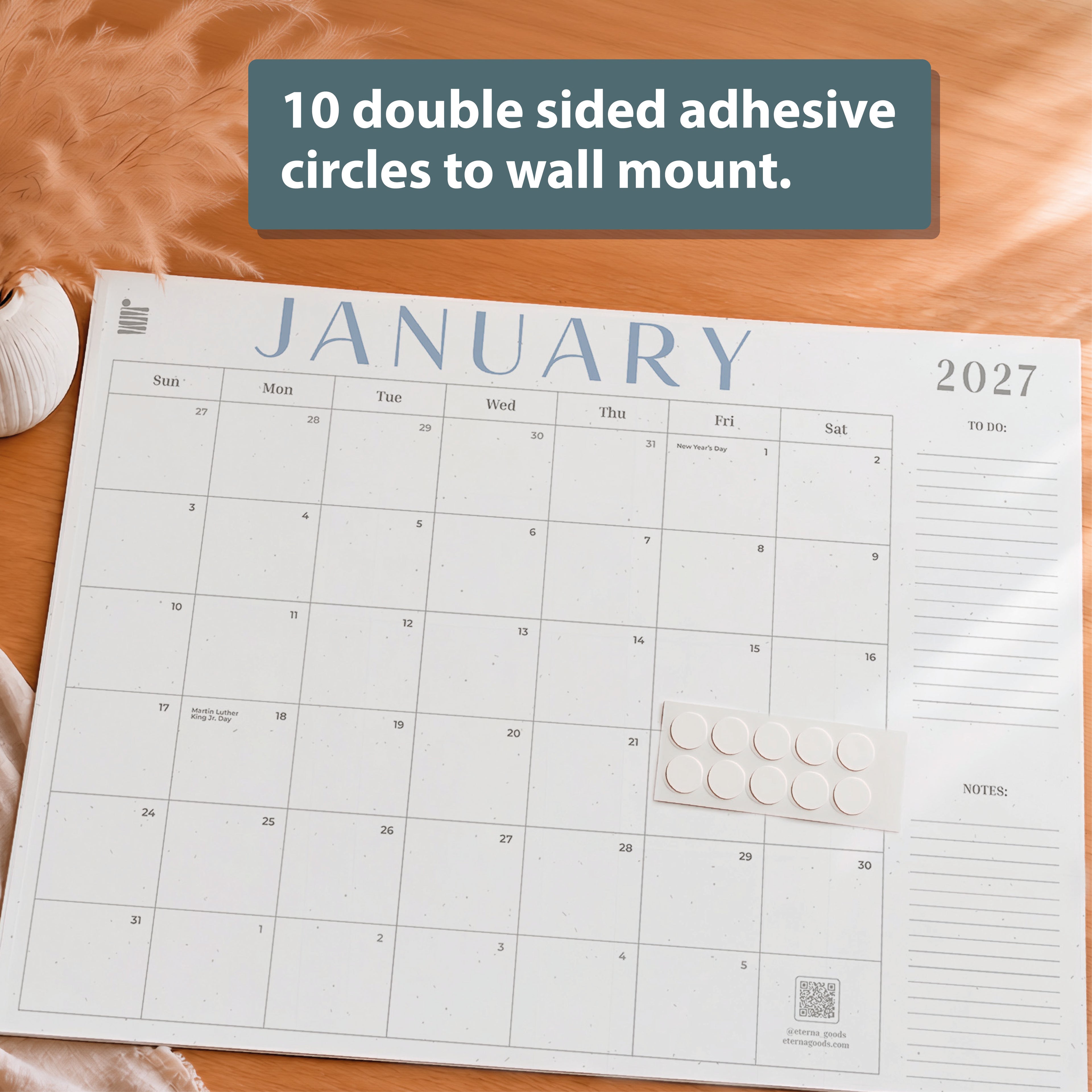 The Eterna Goods 2026-2027 18-Month Flat Desk Calendar (22"x17") offers large writing space, includes 10 double-sided adhesive circles for wall mounting highlighted in a text box, and is the perfect planner for your workspace.