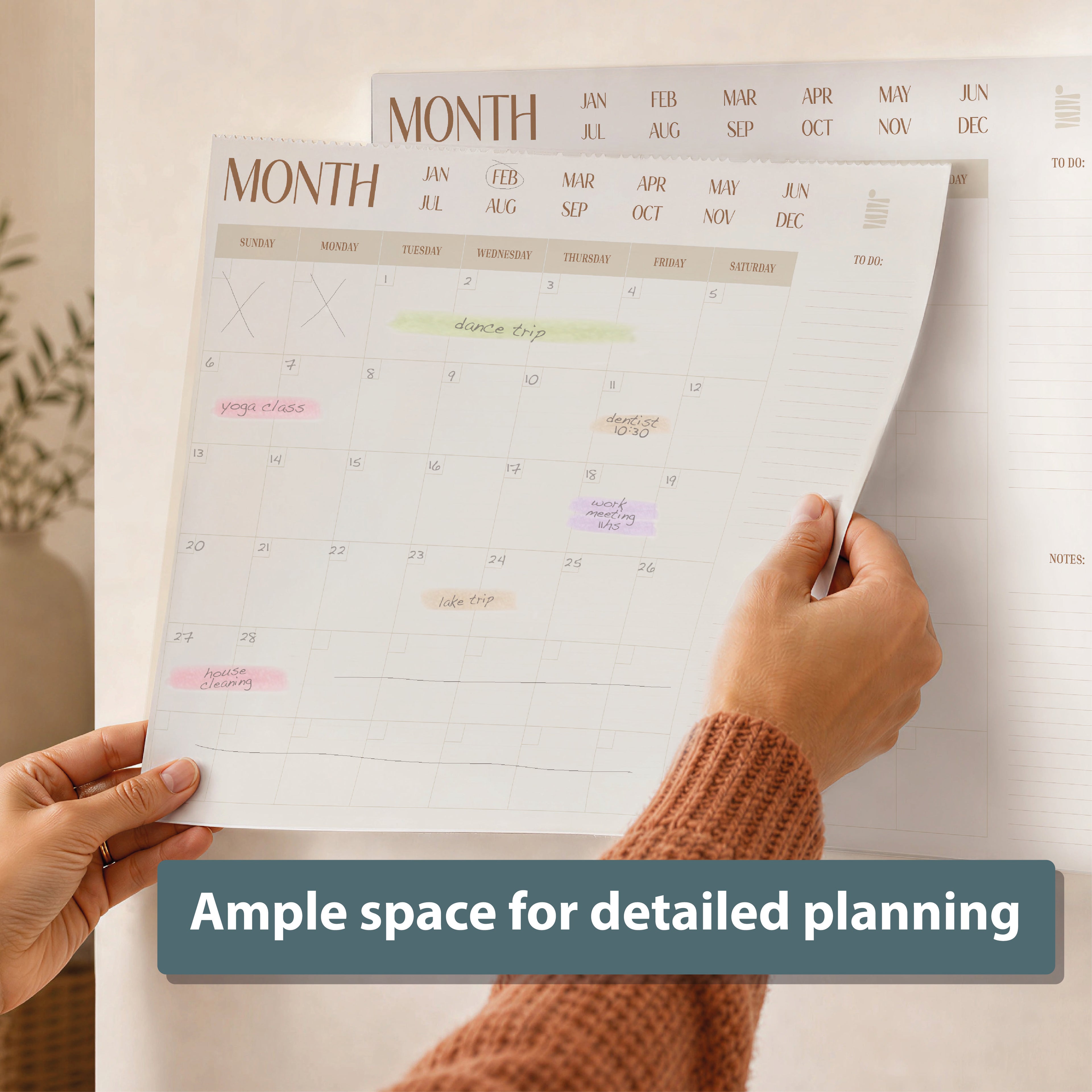 Someone holds the Eterna Goods Undated 12-Month Flat Desk Calendar (22" x 17") filled with handwritten notes and color highlights; a text overlay states, "Ample space for detailed planning.